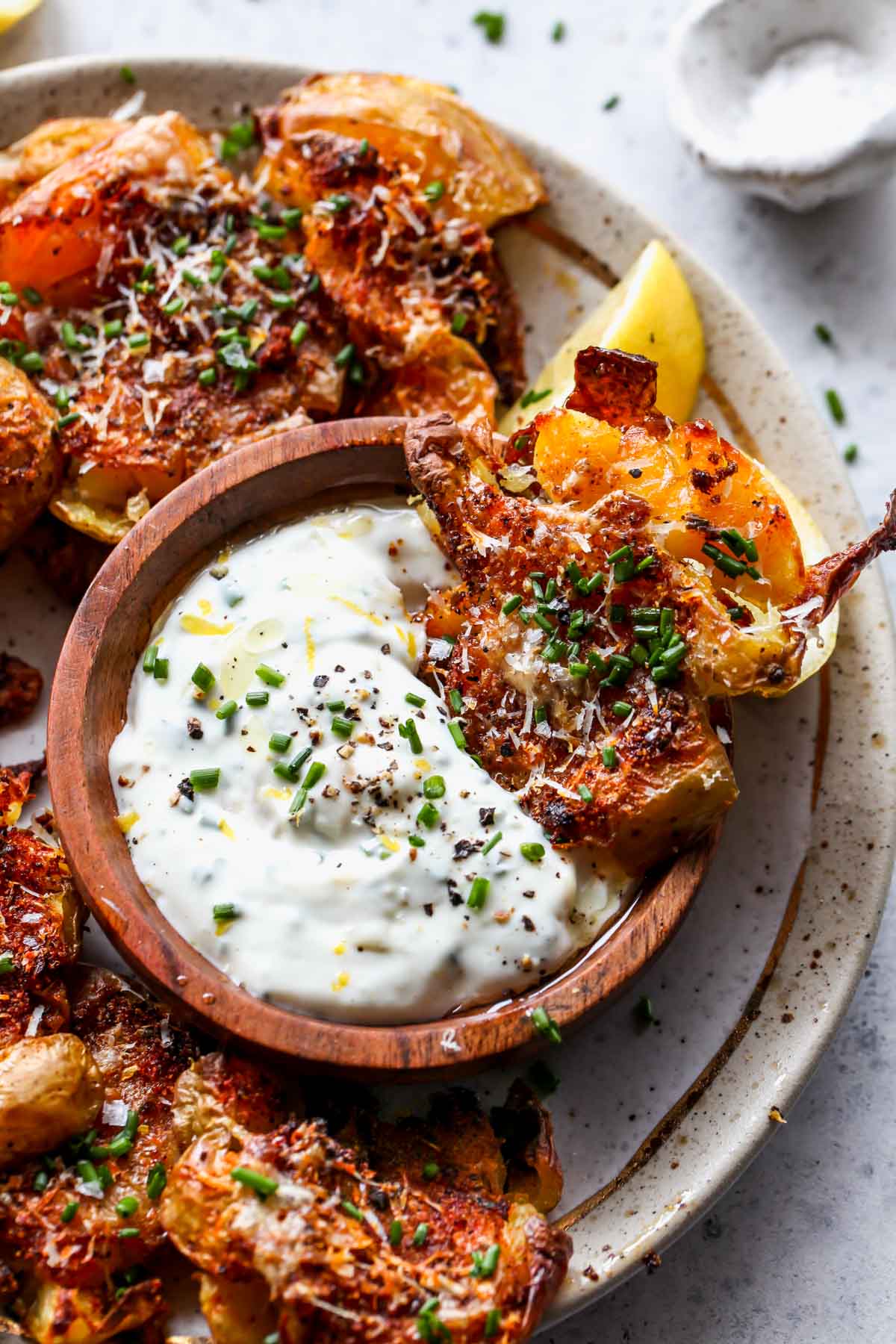 Smashed potato being dipped into a bowl of garlic aioli