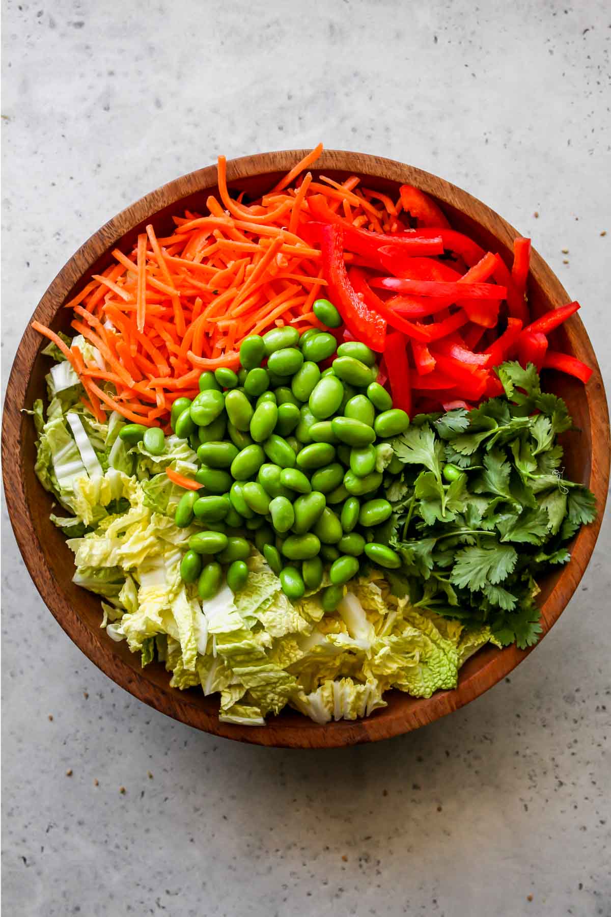 Shredded cabbage. red pepper, carrots, and edamame in a large mixing bowl