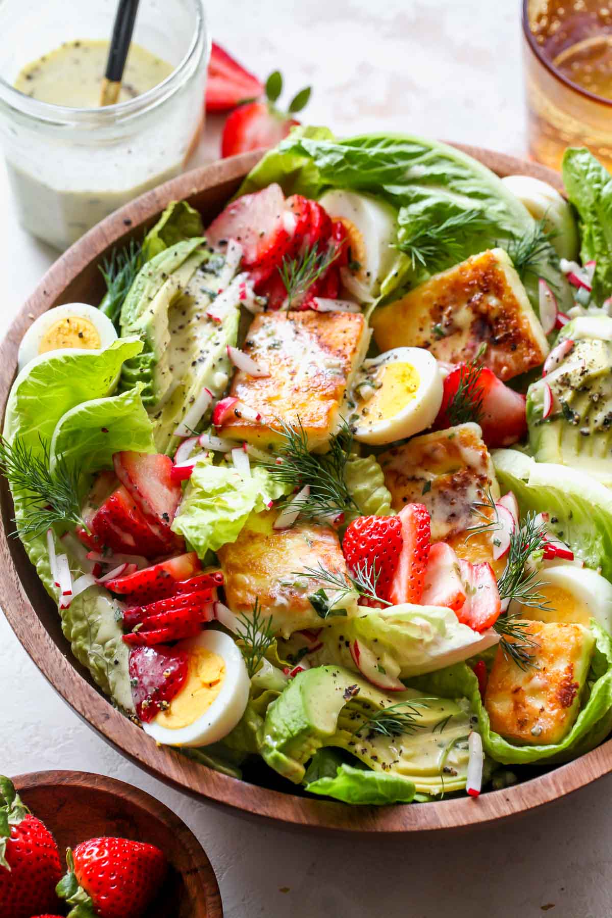 Strawberry Cobb Salad with Tarragon Dressing being assembled in a wooden serving bowl