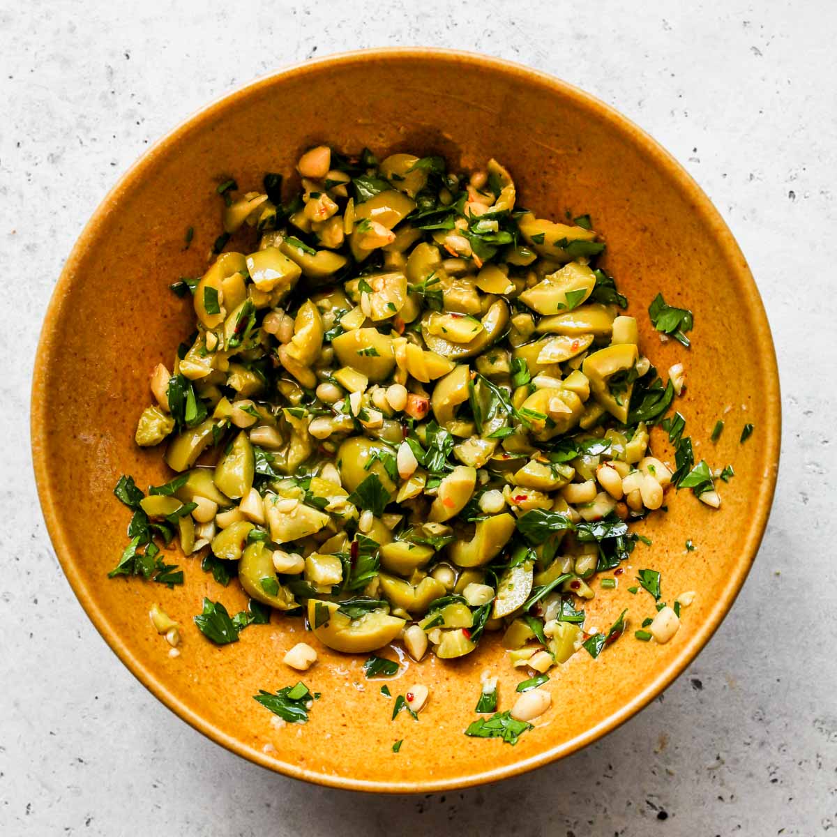 Olive salsa being mixed in a gold bowl