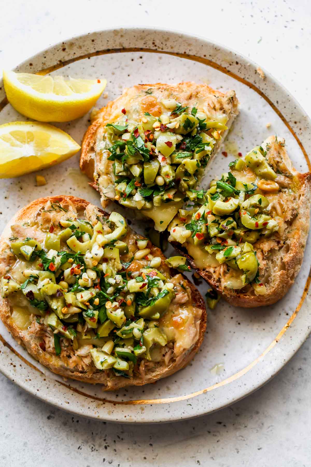 Tuna toast topped with cheese and olive salsa on a plate