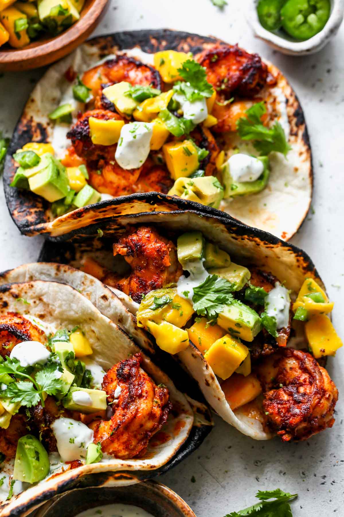 Three shrimp tacos assembled on a serving board