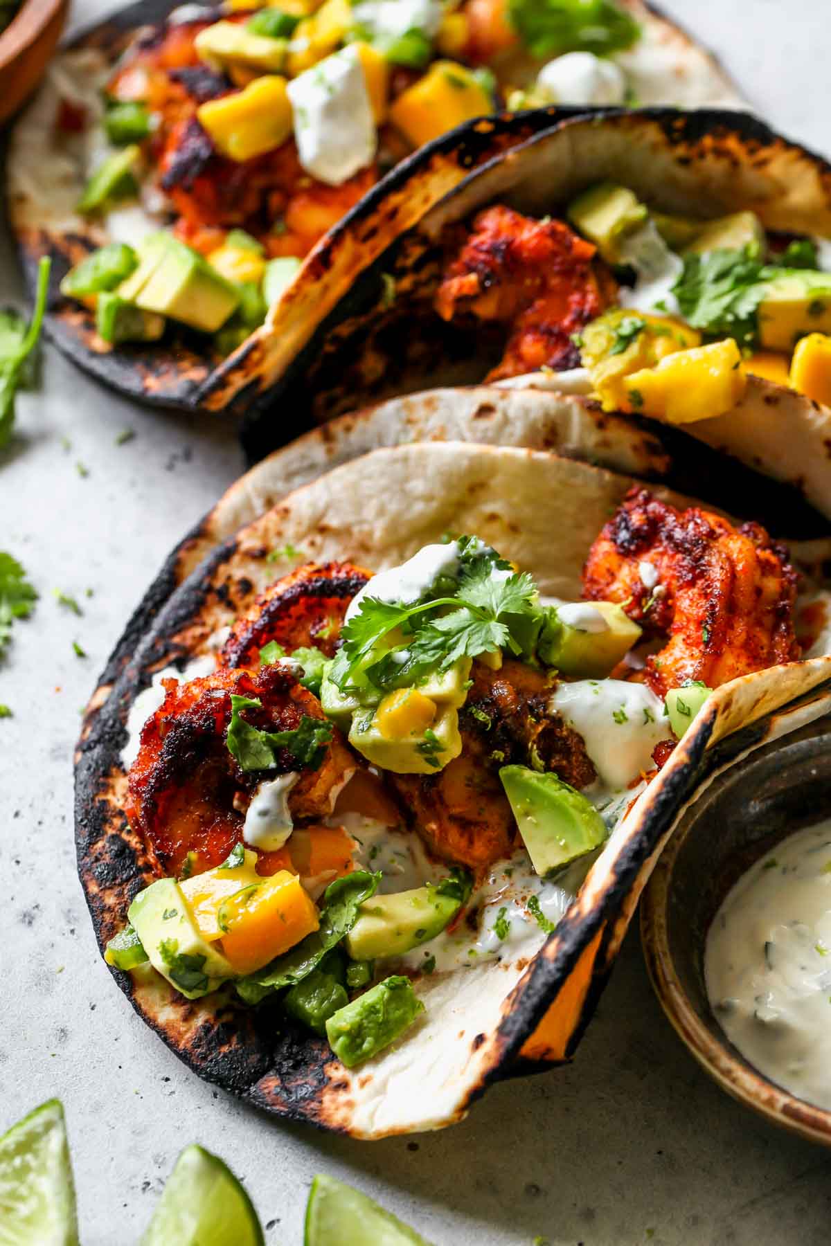 Chipotle shrimp taco topped with avocado-mango salsa on a serving board
