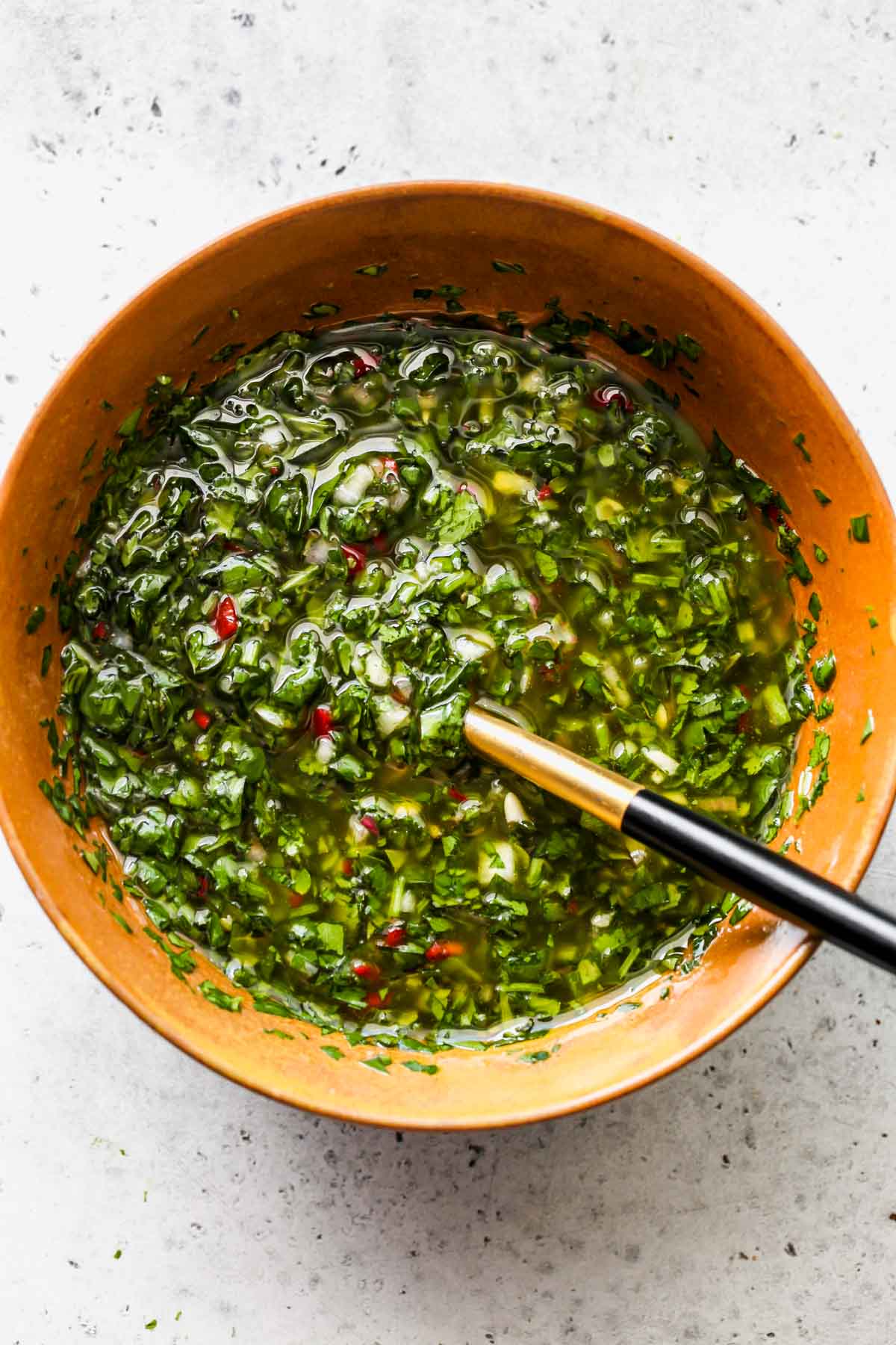 Cilantro Chimichurri in a gold bowl with a spoon resting on the side