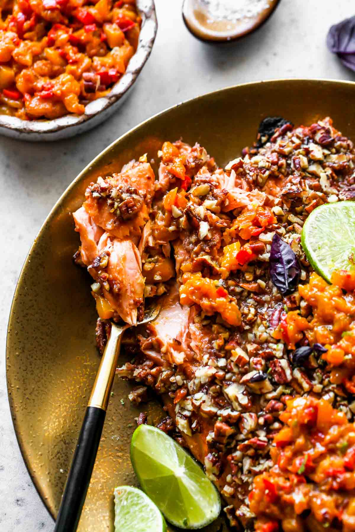 A fork breaking apart a piece of pecan-crusted salmon