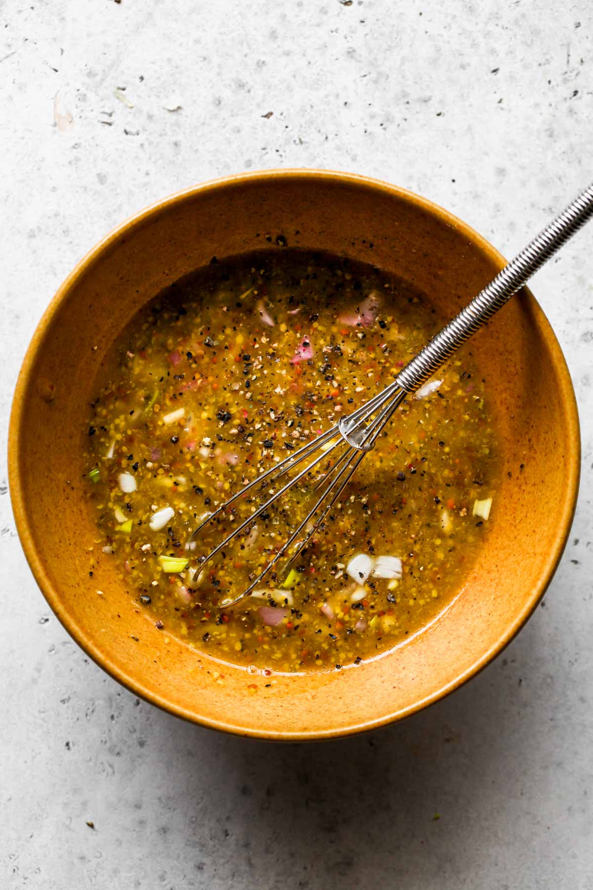 Lemon-shallot dressing being whisked in a gold bowl