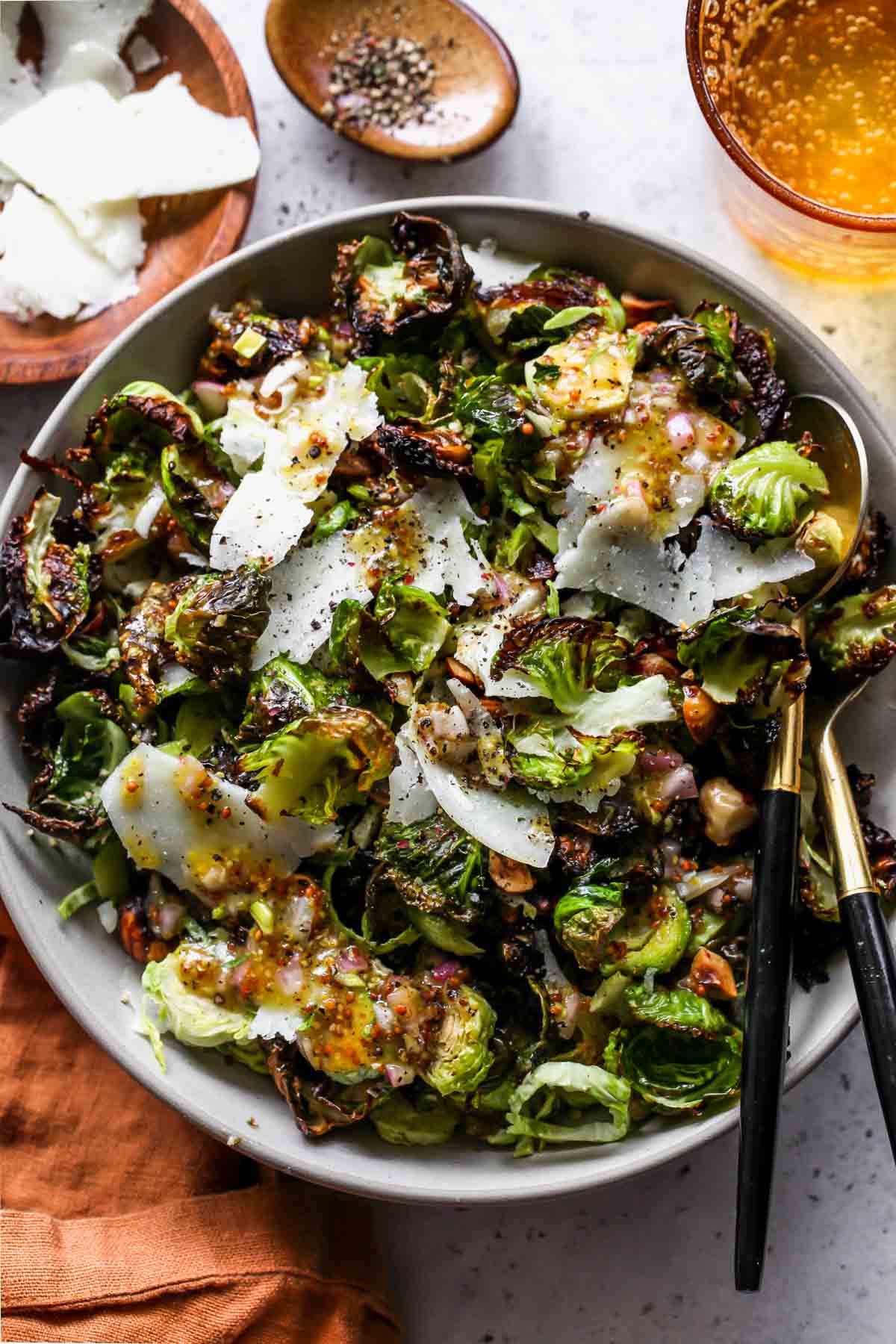 Warm brussels sprouts salad with shredded cheese in a white serving bowl