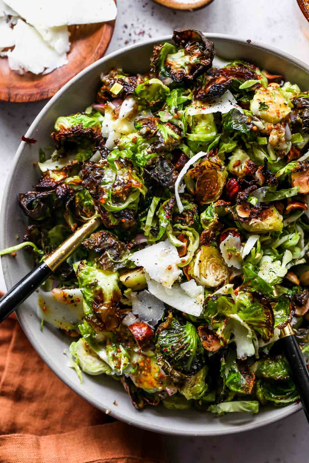 Raw and Roasted Brussels Sprouts Salad being tossed with dressing in a bowl
