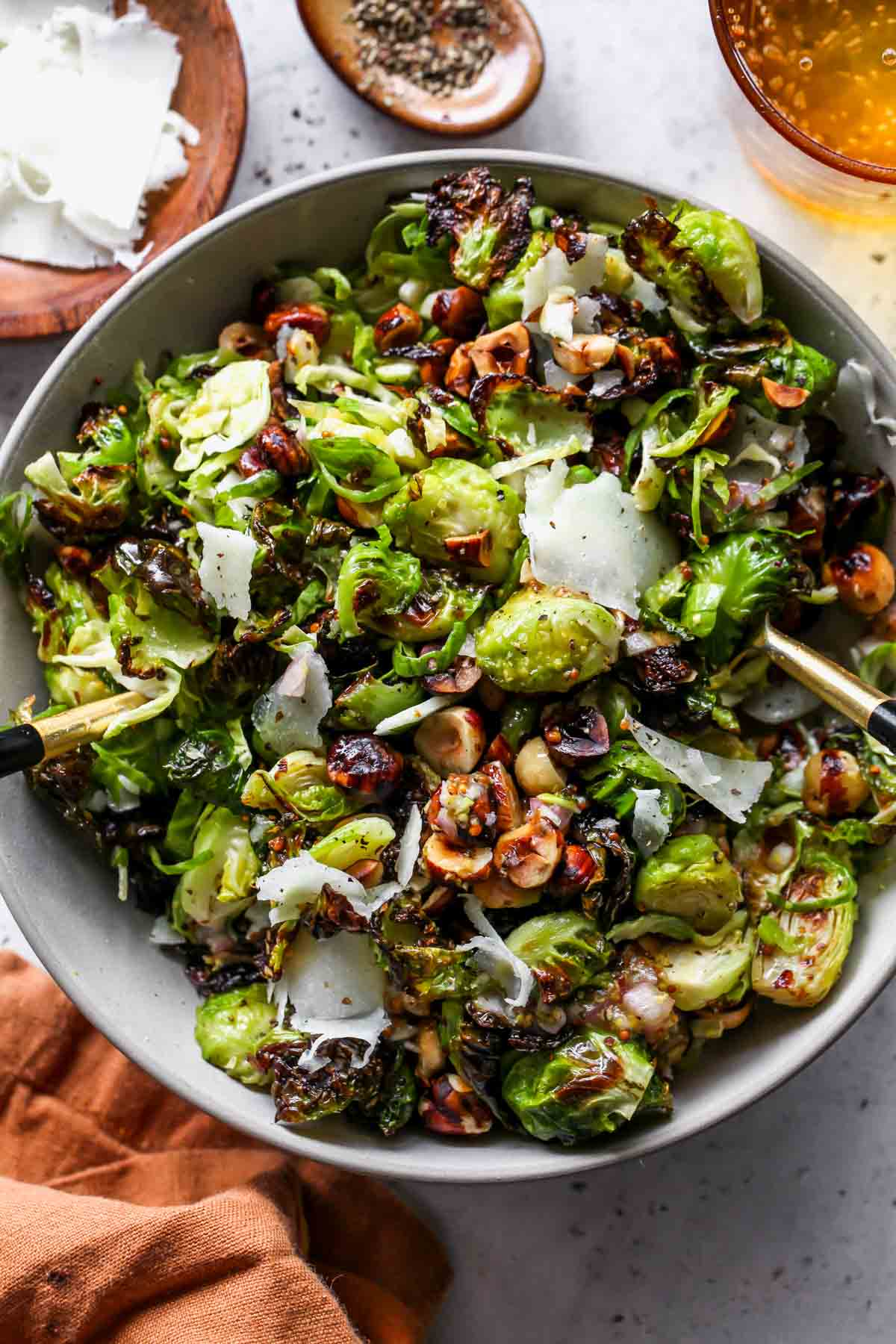 Brussels Sprouts Salad topped with shredded cheese and hazelnuts in a bowl