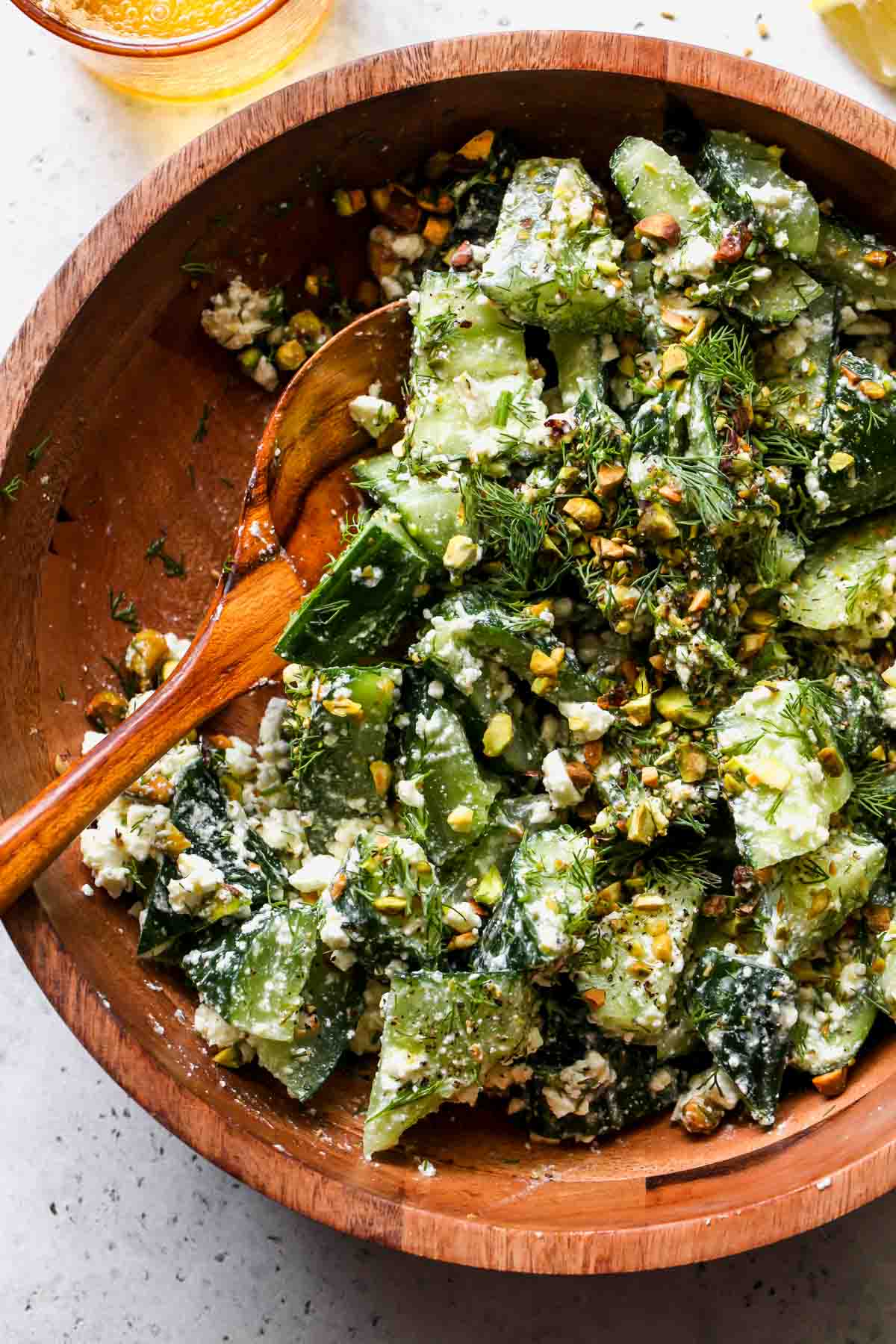 A serving spoon taking a portion of smashed cucumber salad.