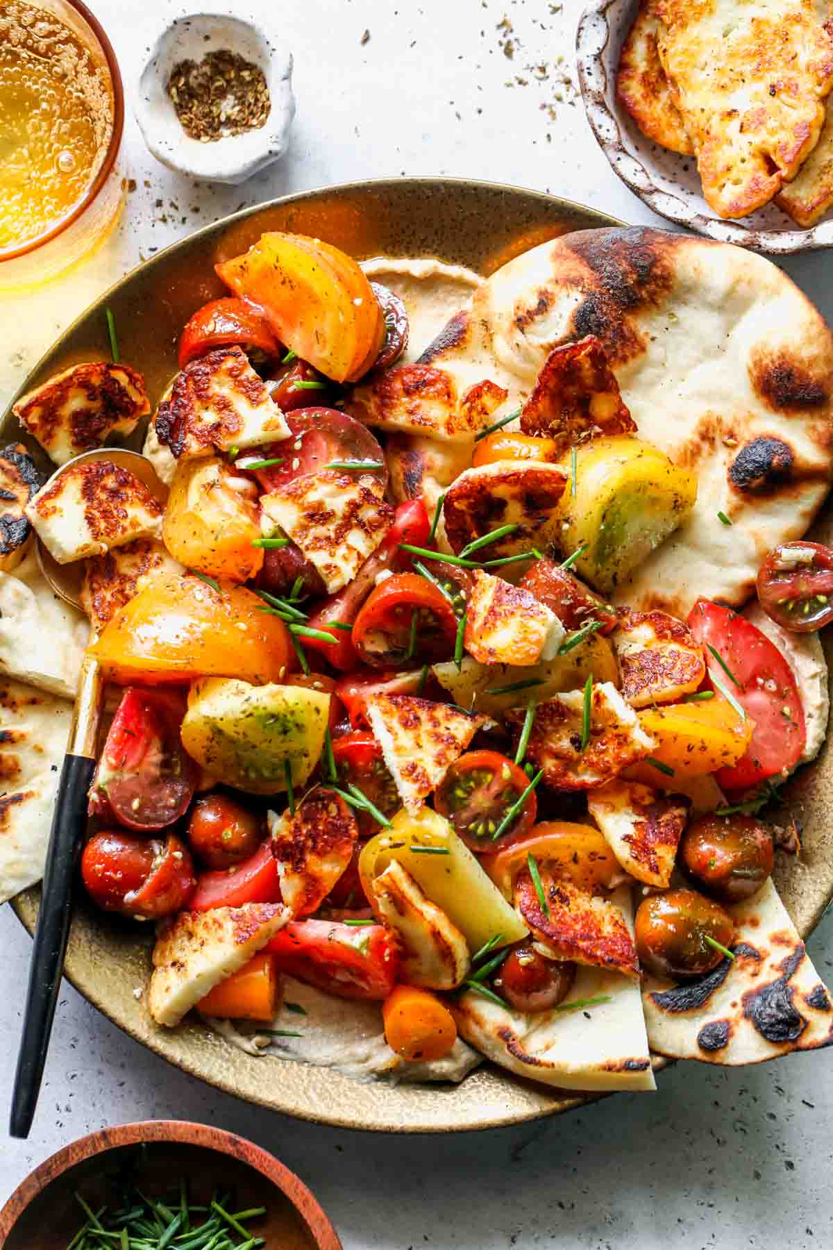 Marinated tomatoes and halloumi on a gold plate with grilled naan bread