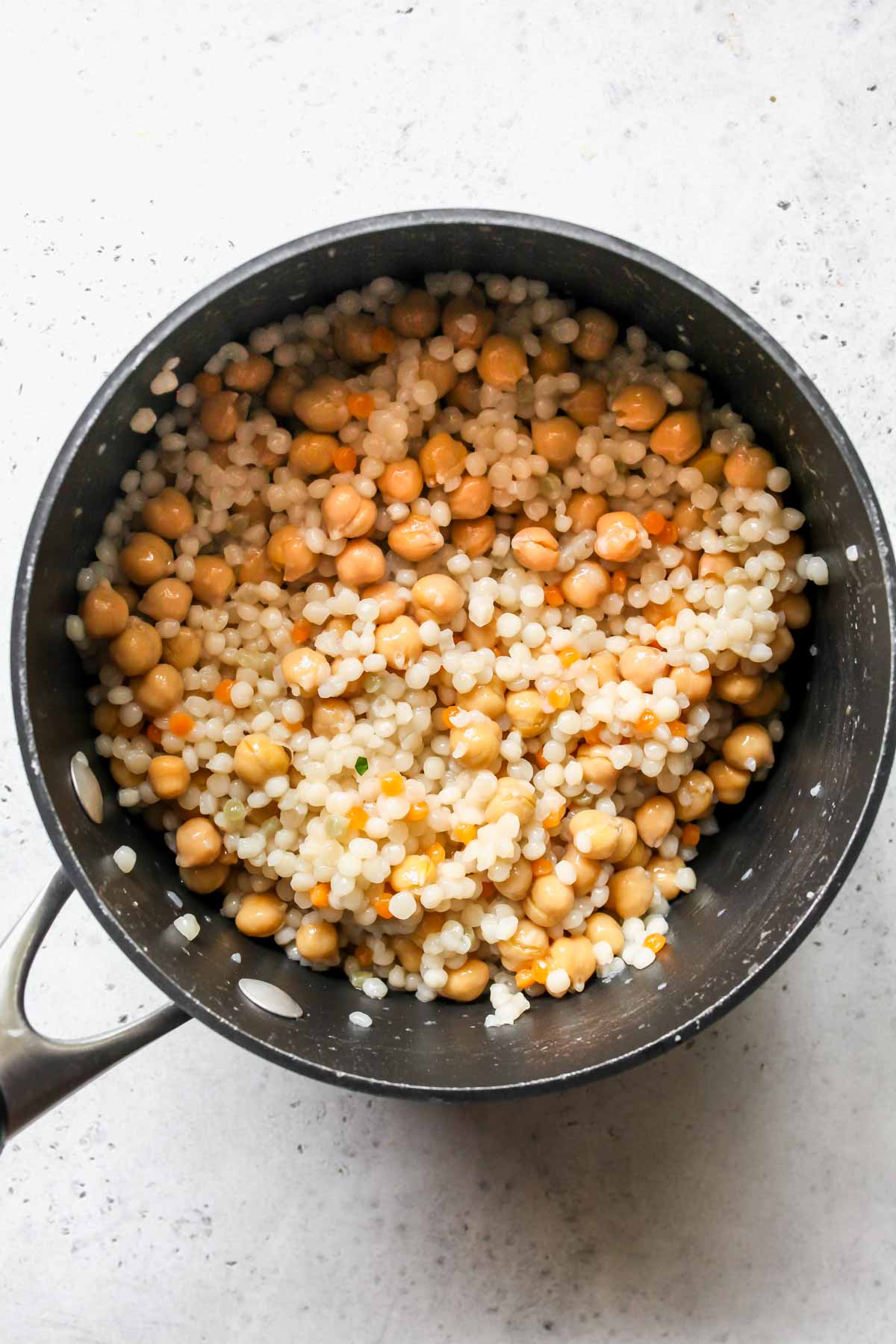Pearl couscous tossed with chickpeas in a saucepan