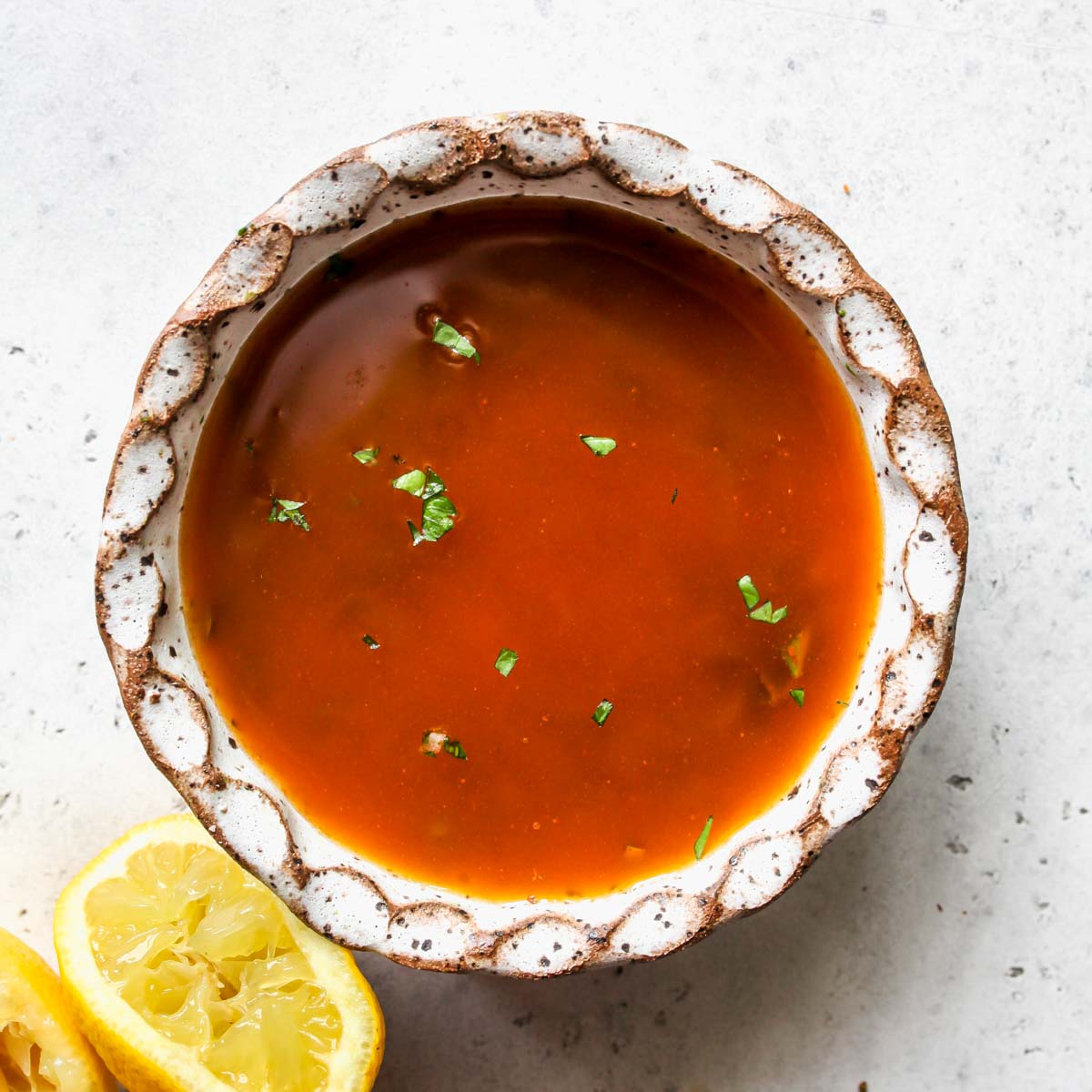 Olive oil, lemon juice, and spices mixed in a small white bowl