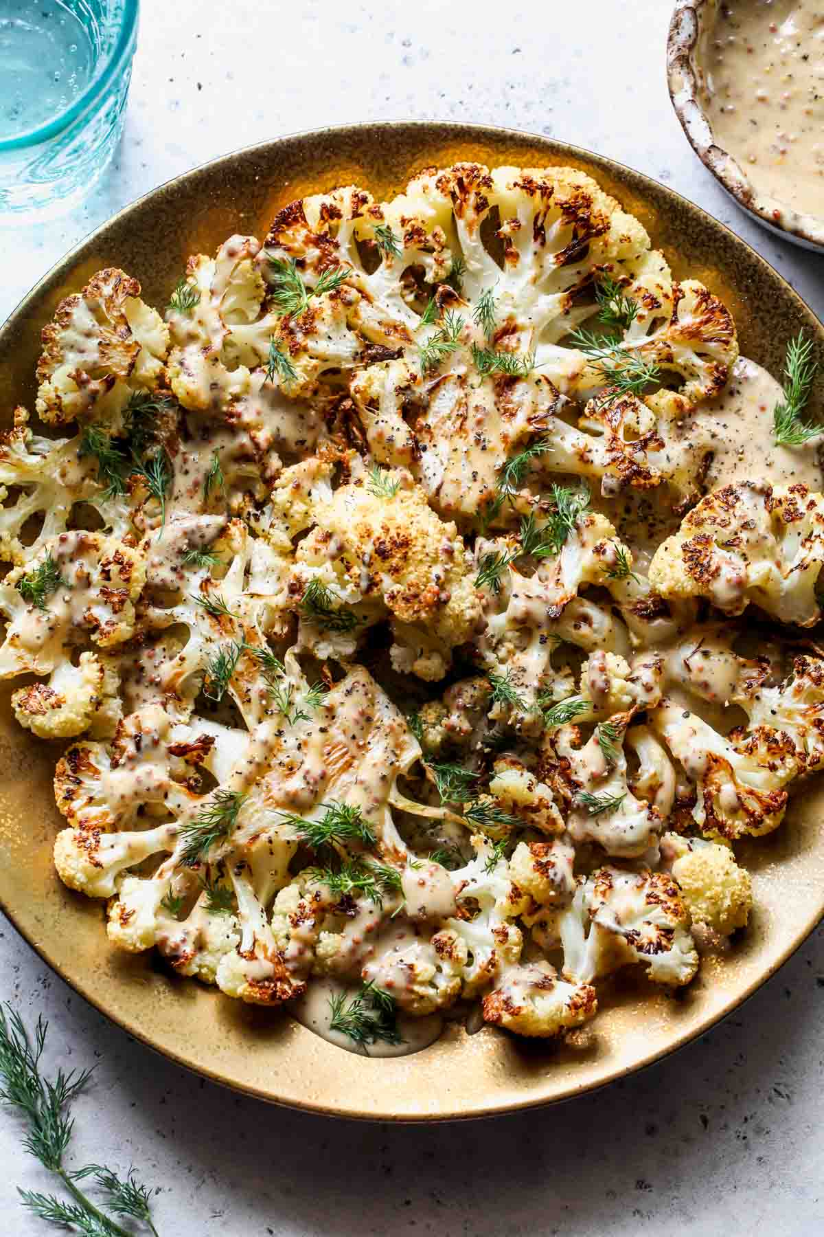 Roasted cauliflower florets on a serving platter topped with tahini sauce