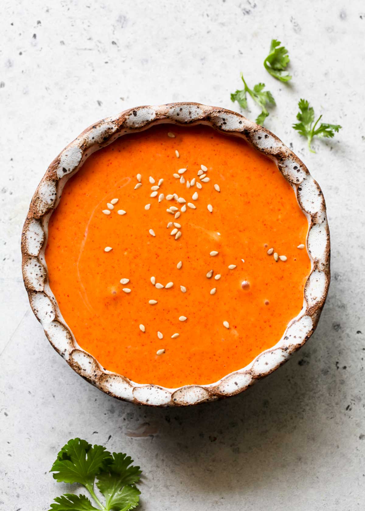 Gochujang aioli in a small white bowl topped with sesame seeds