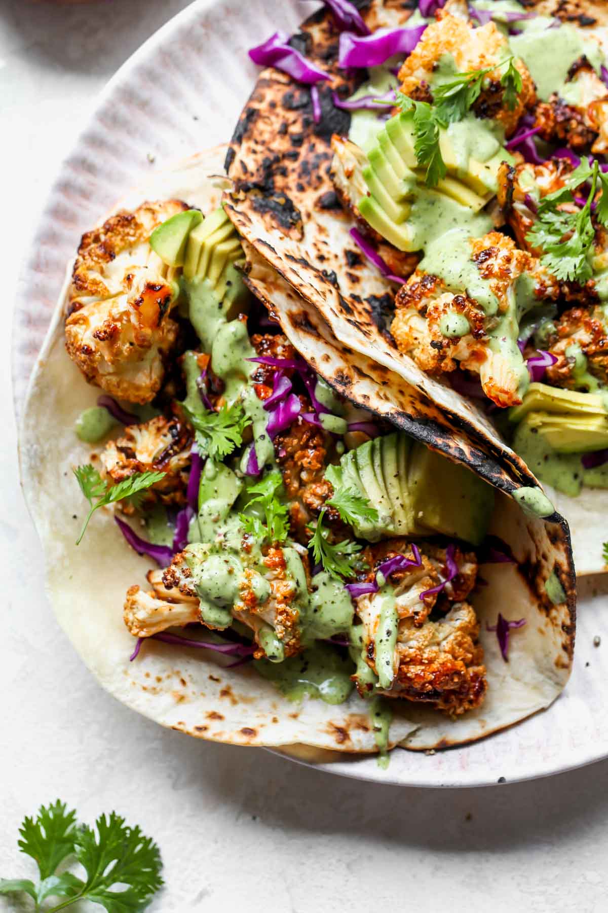 vegan cauliflower tacos topped with garnishes on a serving plate