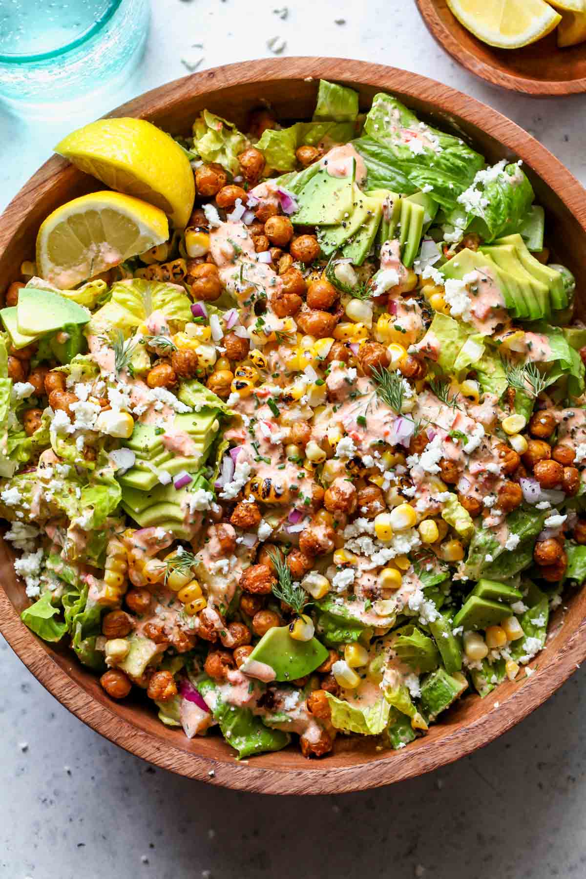 Romaine, corn, chickpeas and avocado with ranch dressing in a serving bowl