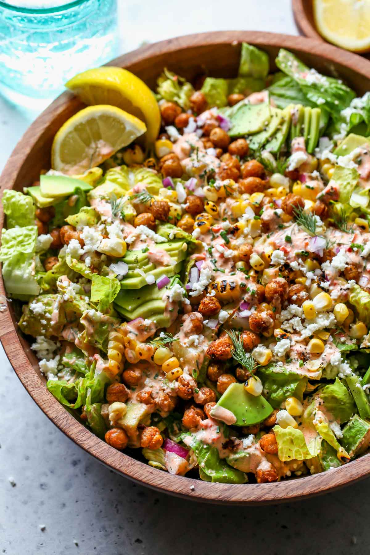 Corn and Avocado Salad topped with crispy chickpeas and harissa ranch in a serving bowl