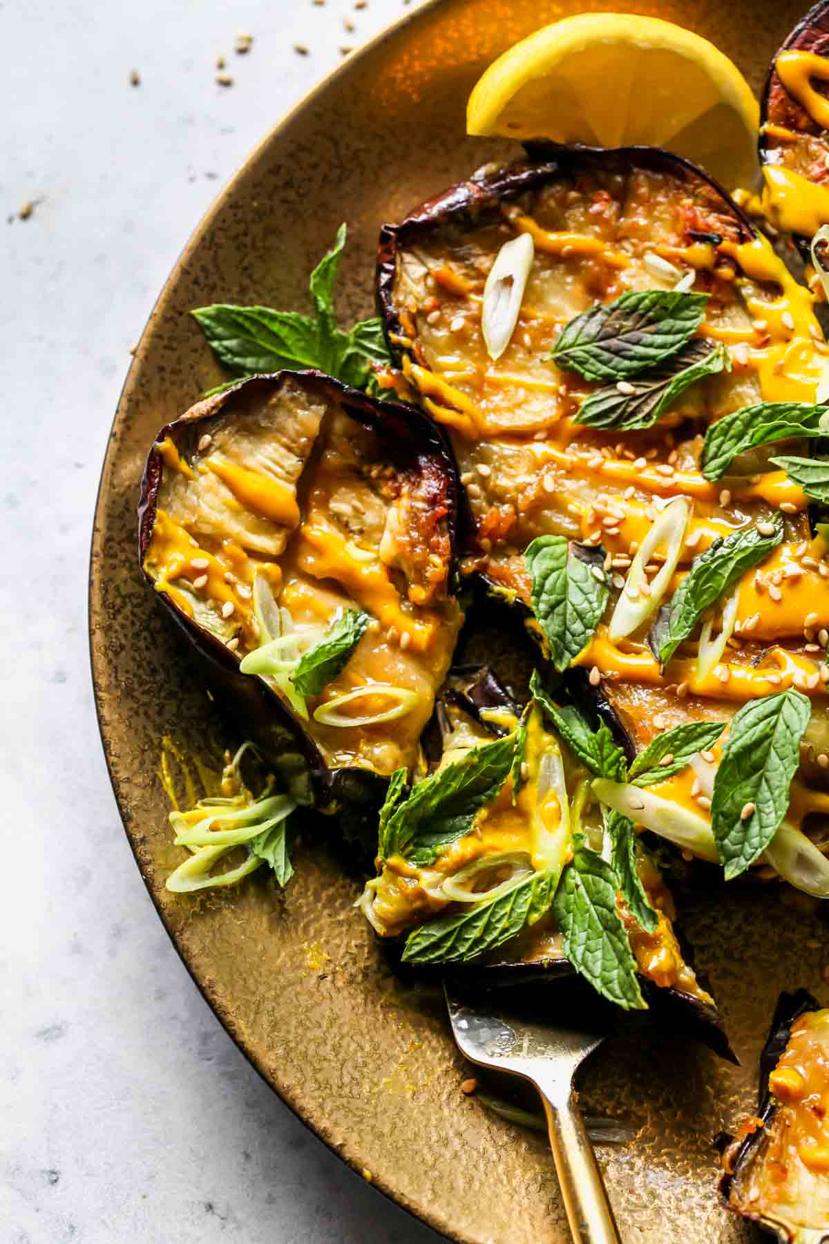 Eggplant being sliced into pieces on a gold plate