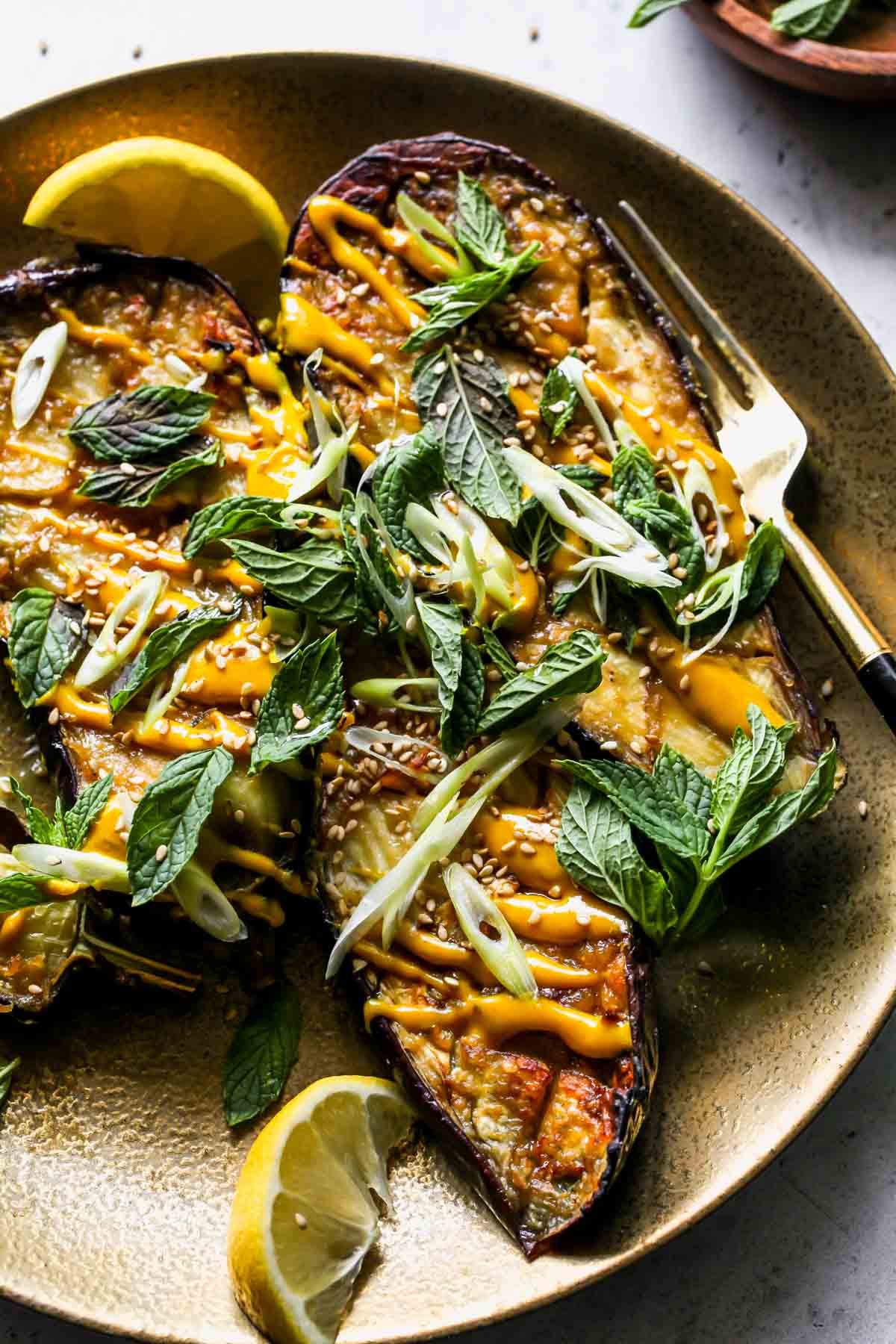 Miso eggplant on a serving platter topped with turmeric sauce and mint