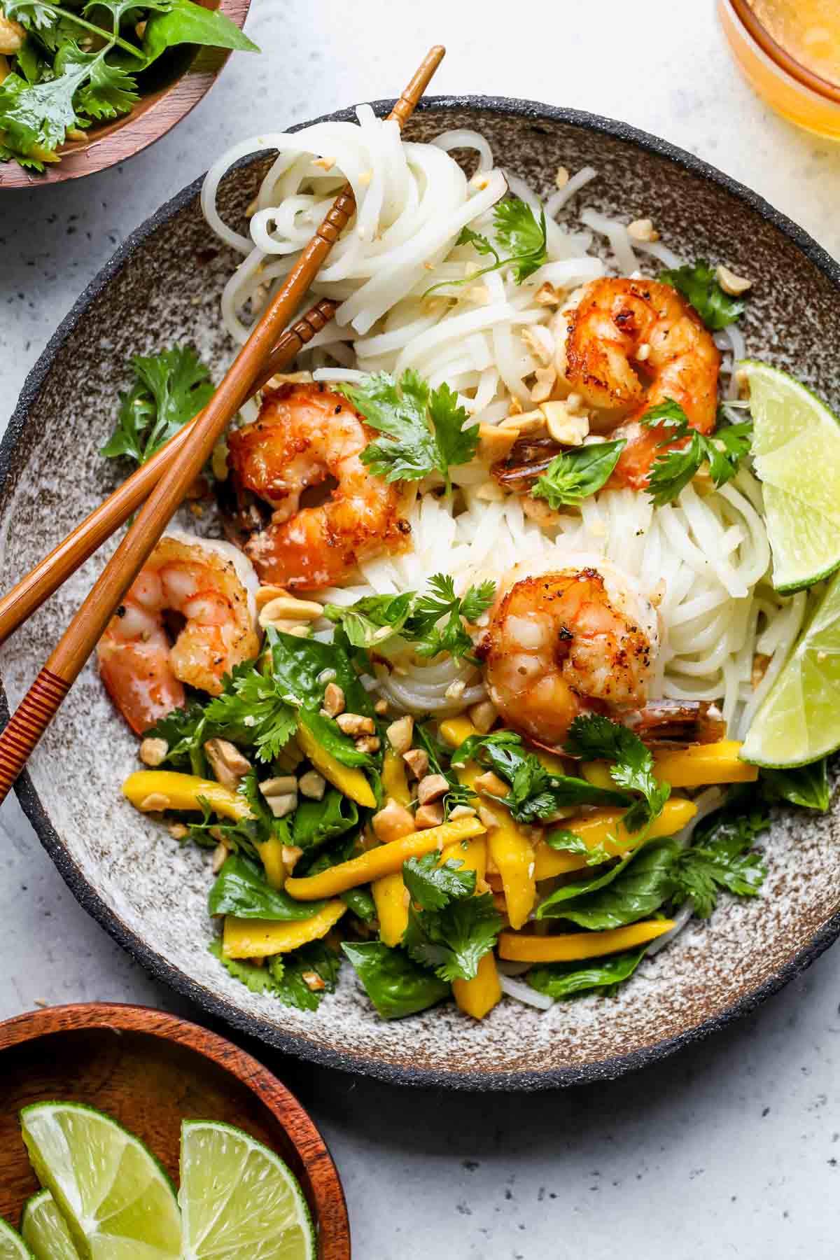 Thai shrimp noodle salad in a bowl with a set of chopsticks twirling noodles