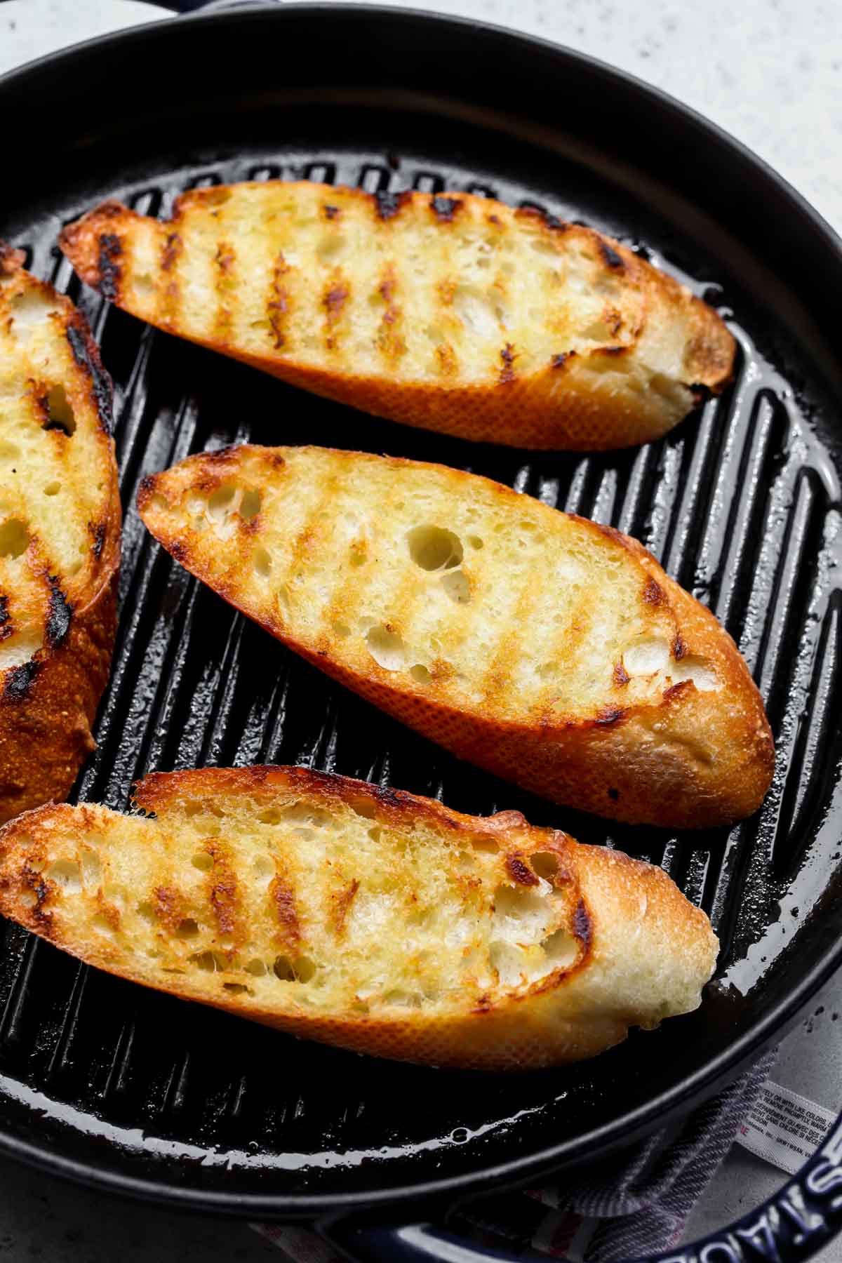 Slices of bread being grilled on a cast iron grill pan