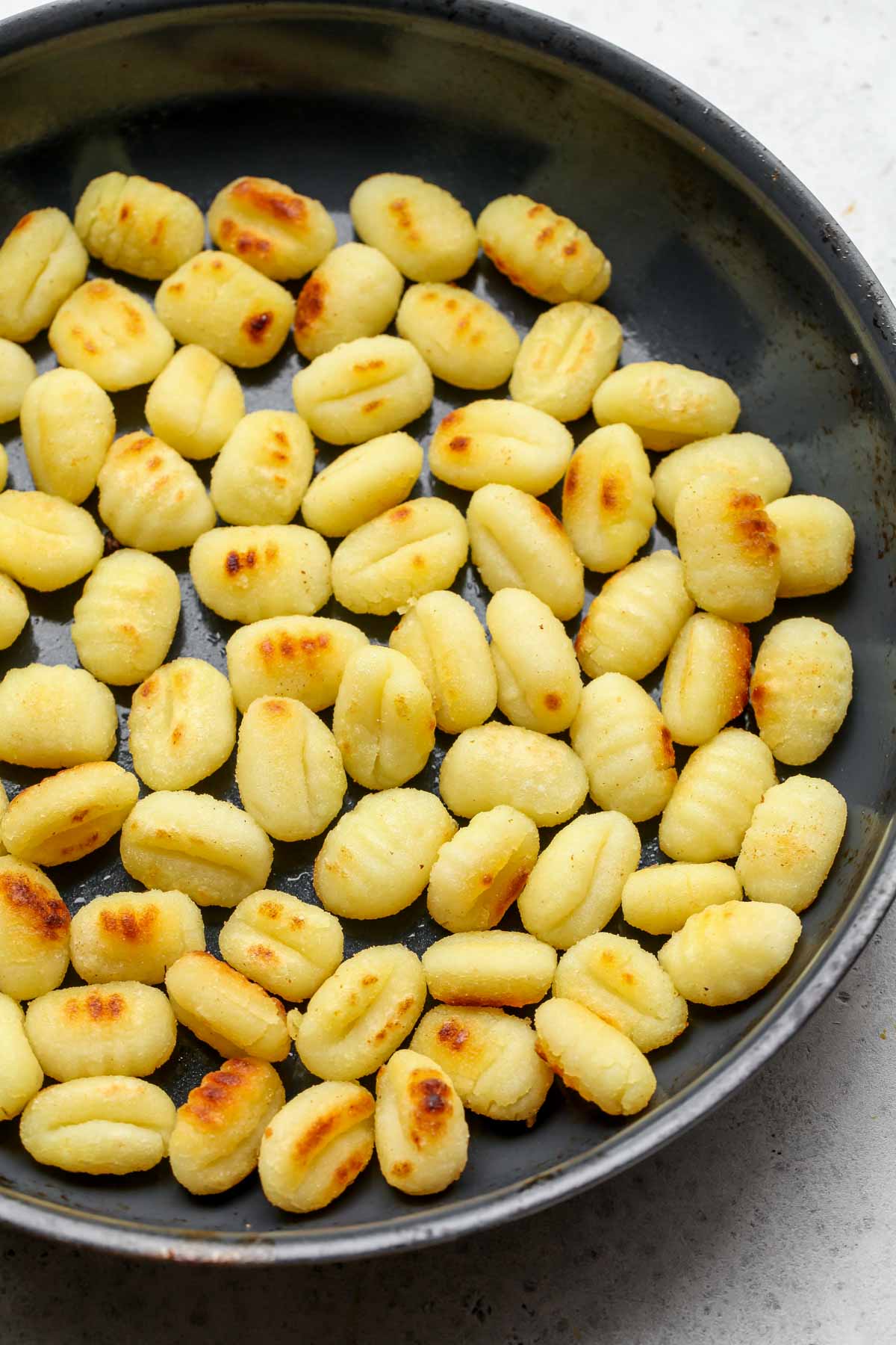 Potato gnocchi being sauteed until golden in a skillet