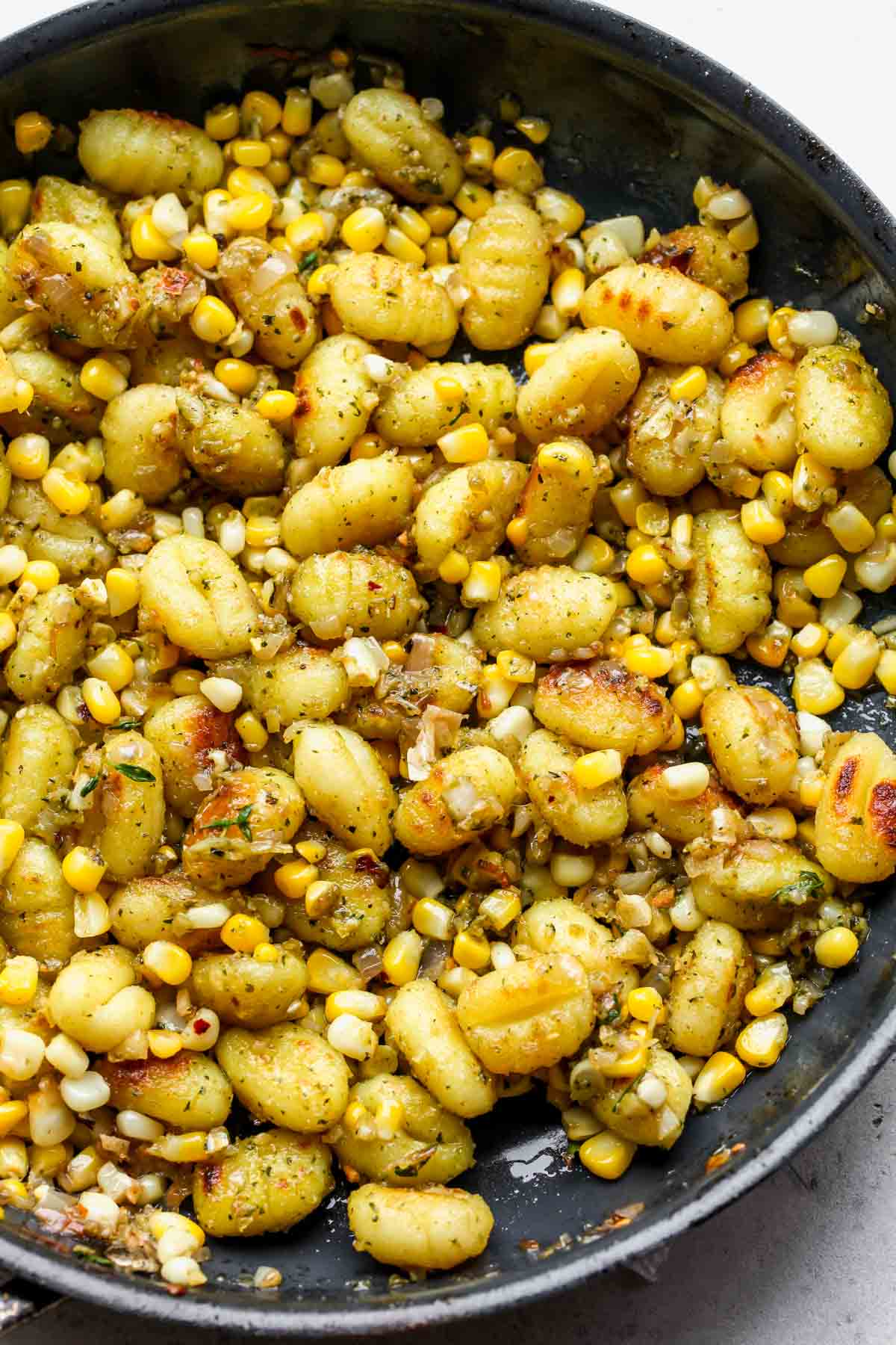 Corn and pesto gnocchi being tossed together in a skillet