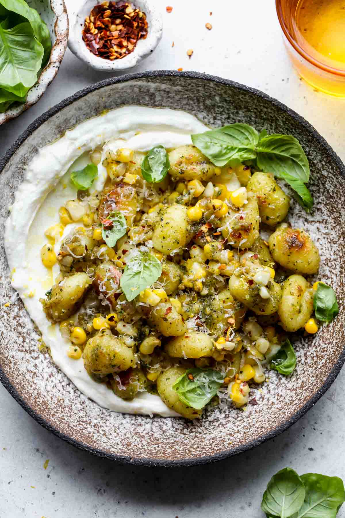 Corn and pesto gnocchi served over lemony whipped ricotta in a gray bowl.