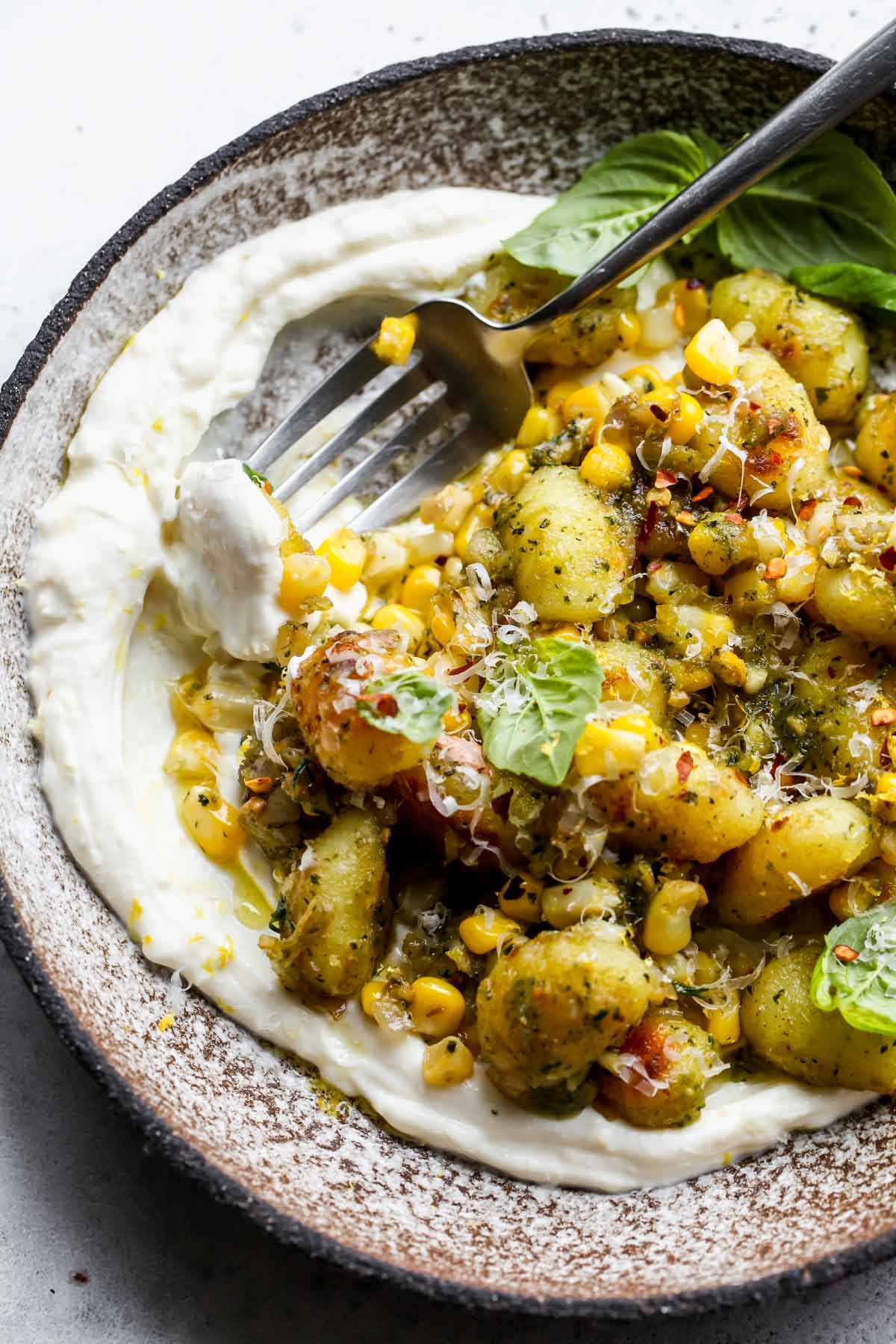 A fork taking a bite of gnocchi and whipped ricotta