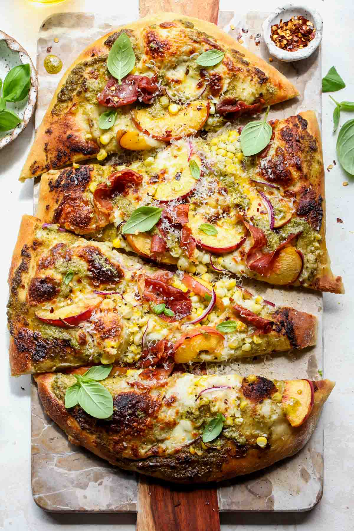 Peach and prosciutto pizza sliced on a stone board