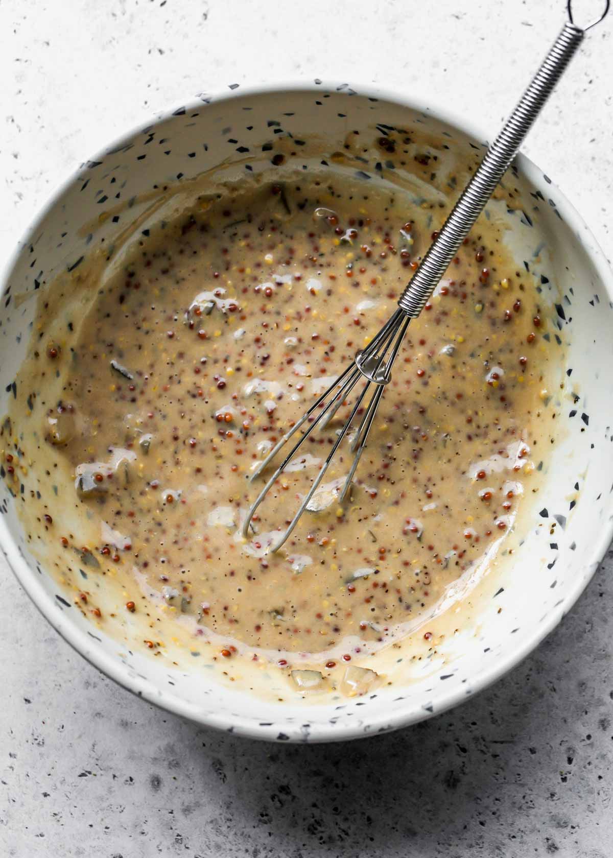 Mustard dressing being whisked in a white bowl