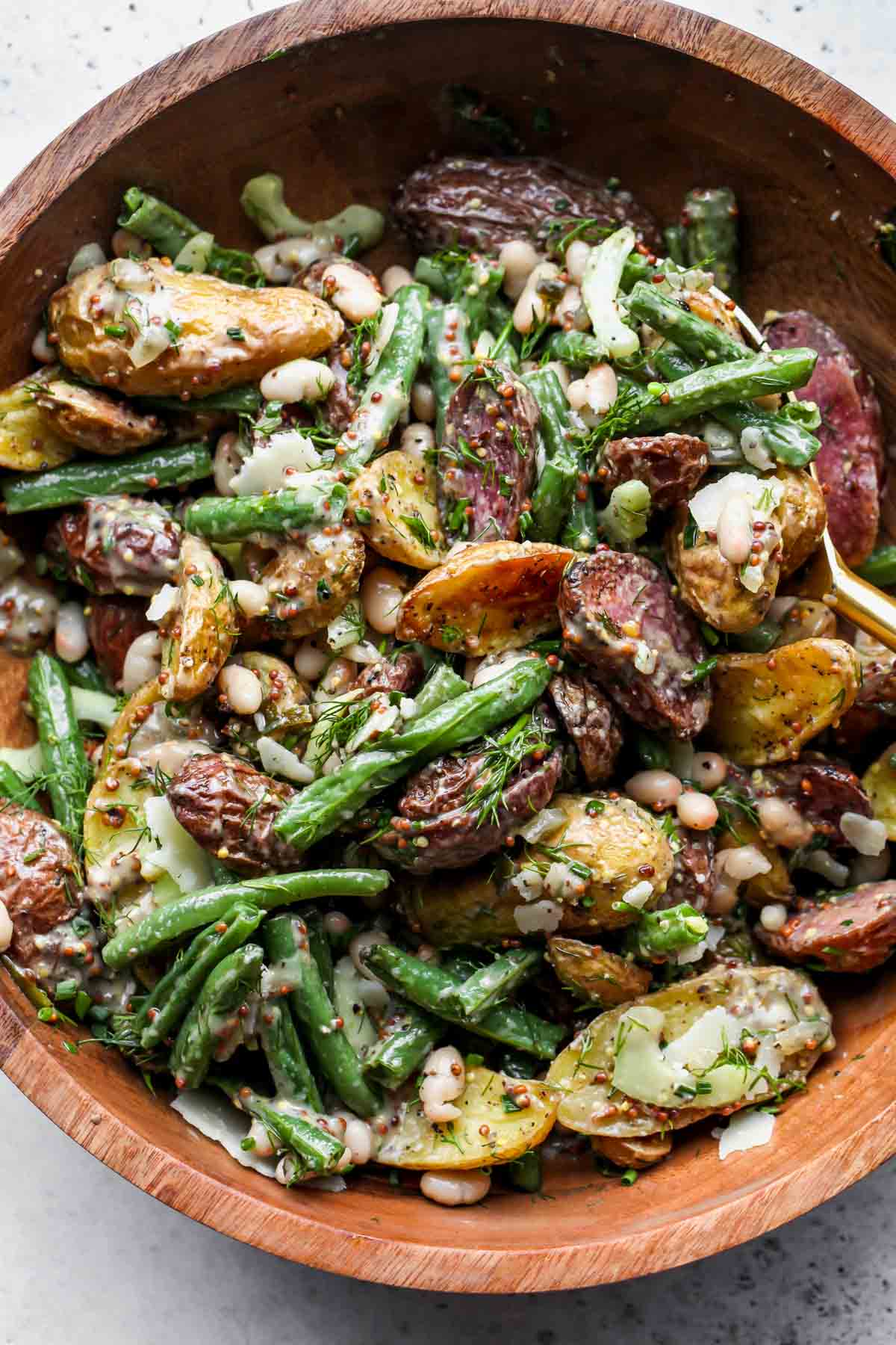 Mayo less potato salad ingredients being tossed in a large serving bowl