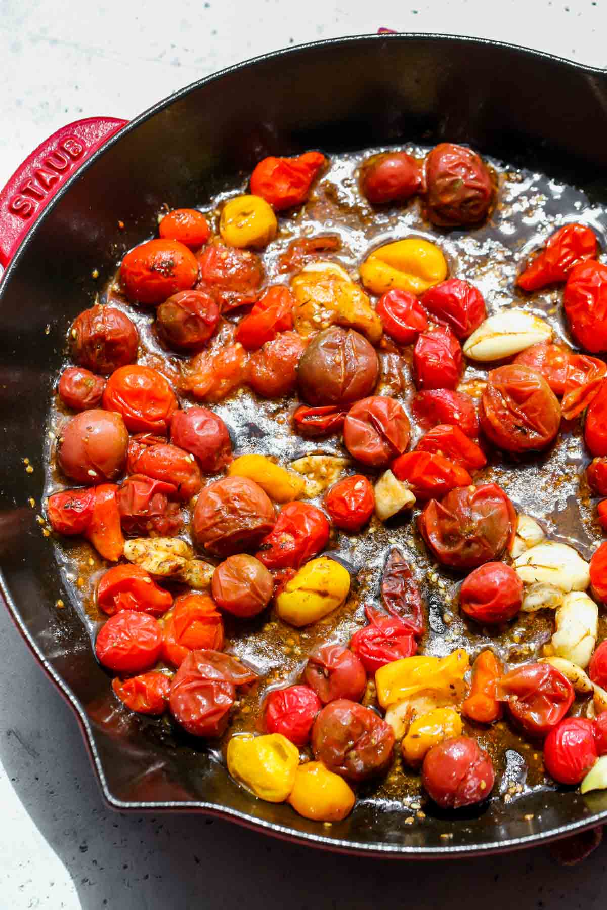 Cherry tomatoes being cooked down in a cast iron skillet.