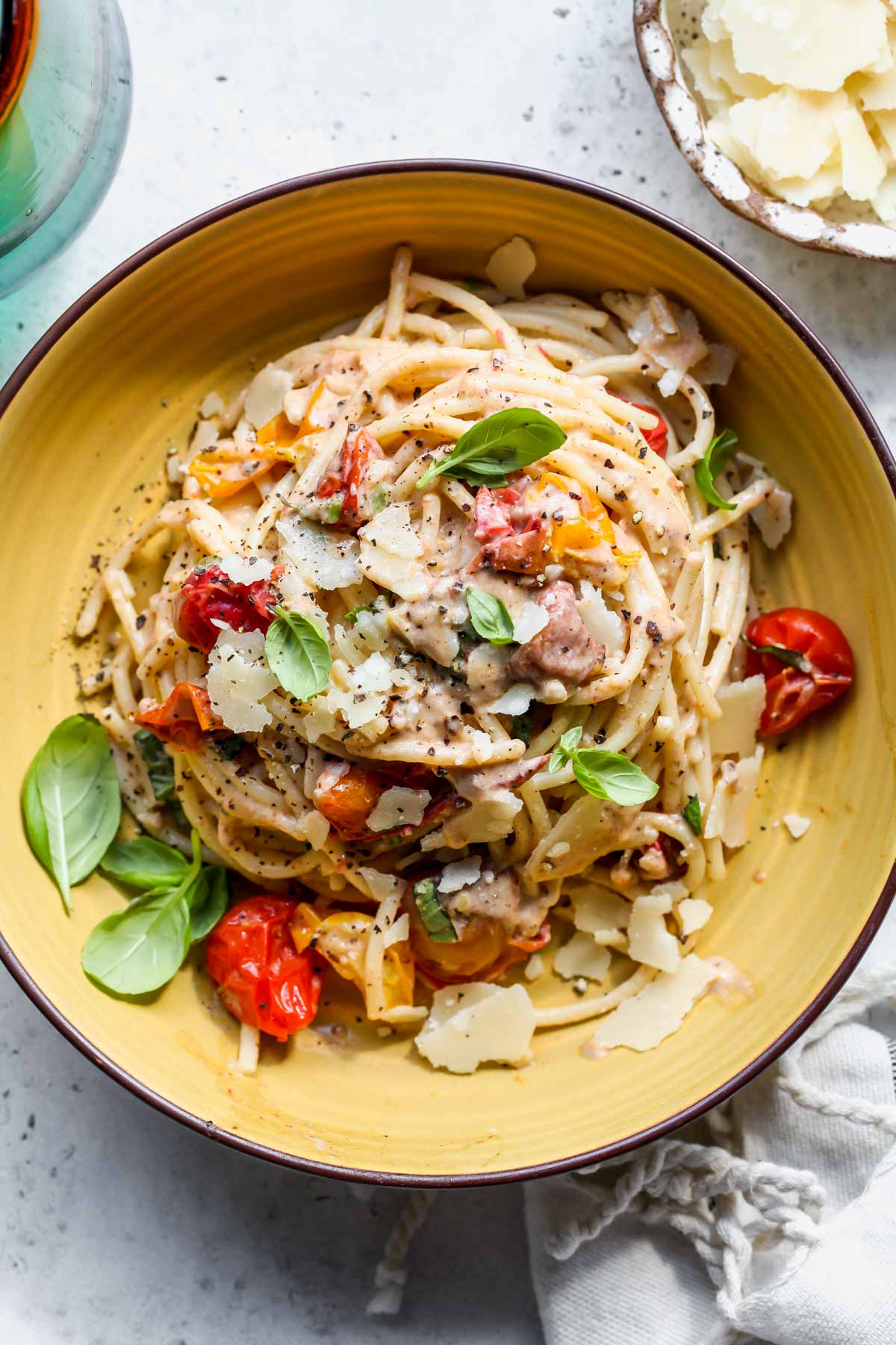 Tahini pasta styled in a yellow bowl topped with parmesan and basil.