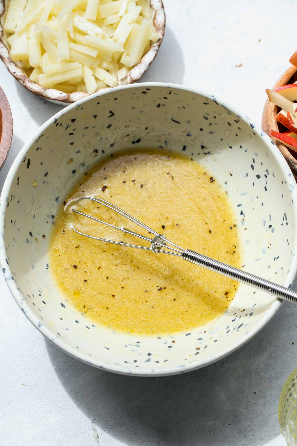 Lemon-dijon dressing being whisked in a white bowl