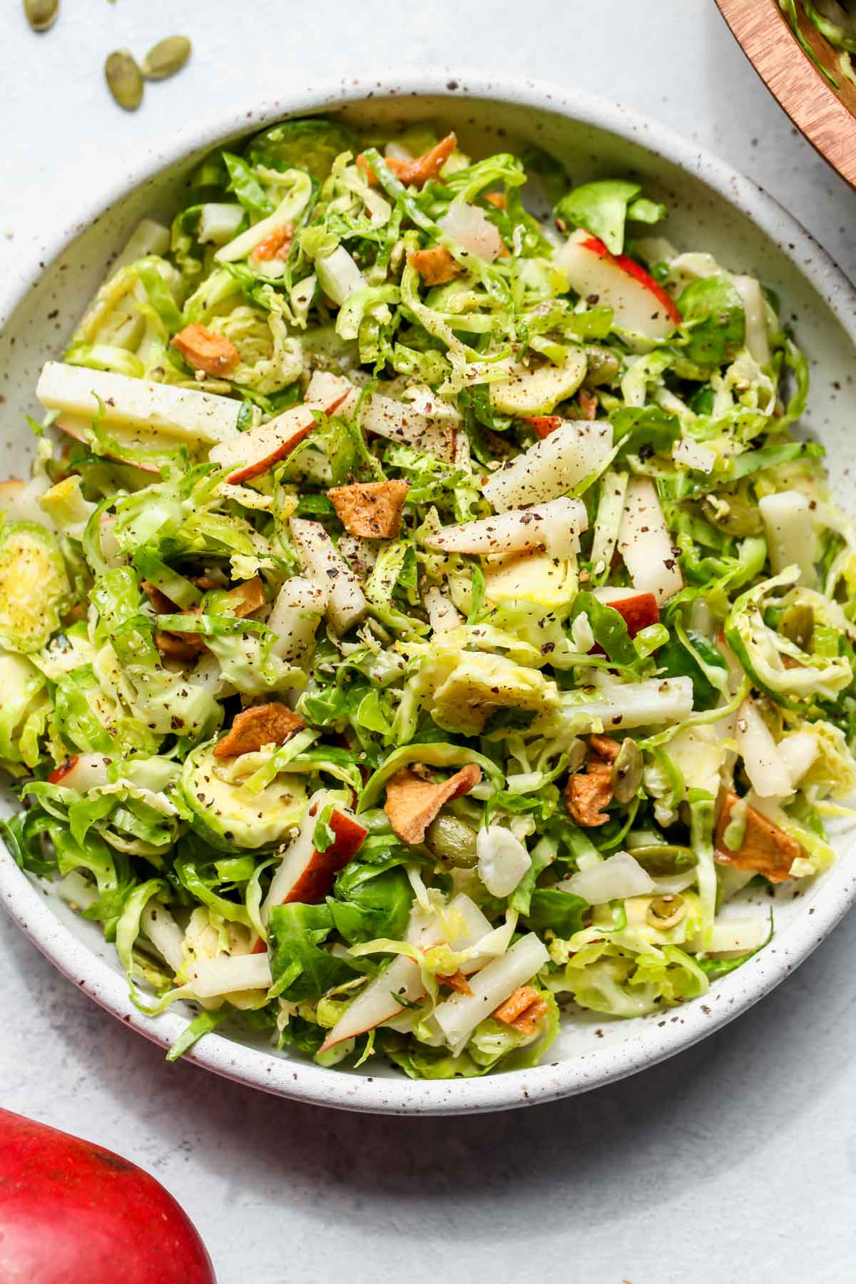 Shaved brussels and pear salad in a white serving bowl