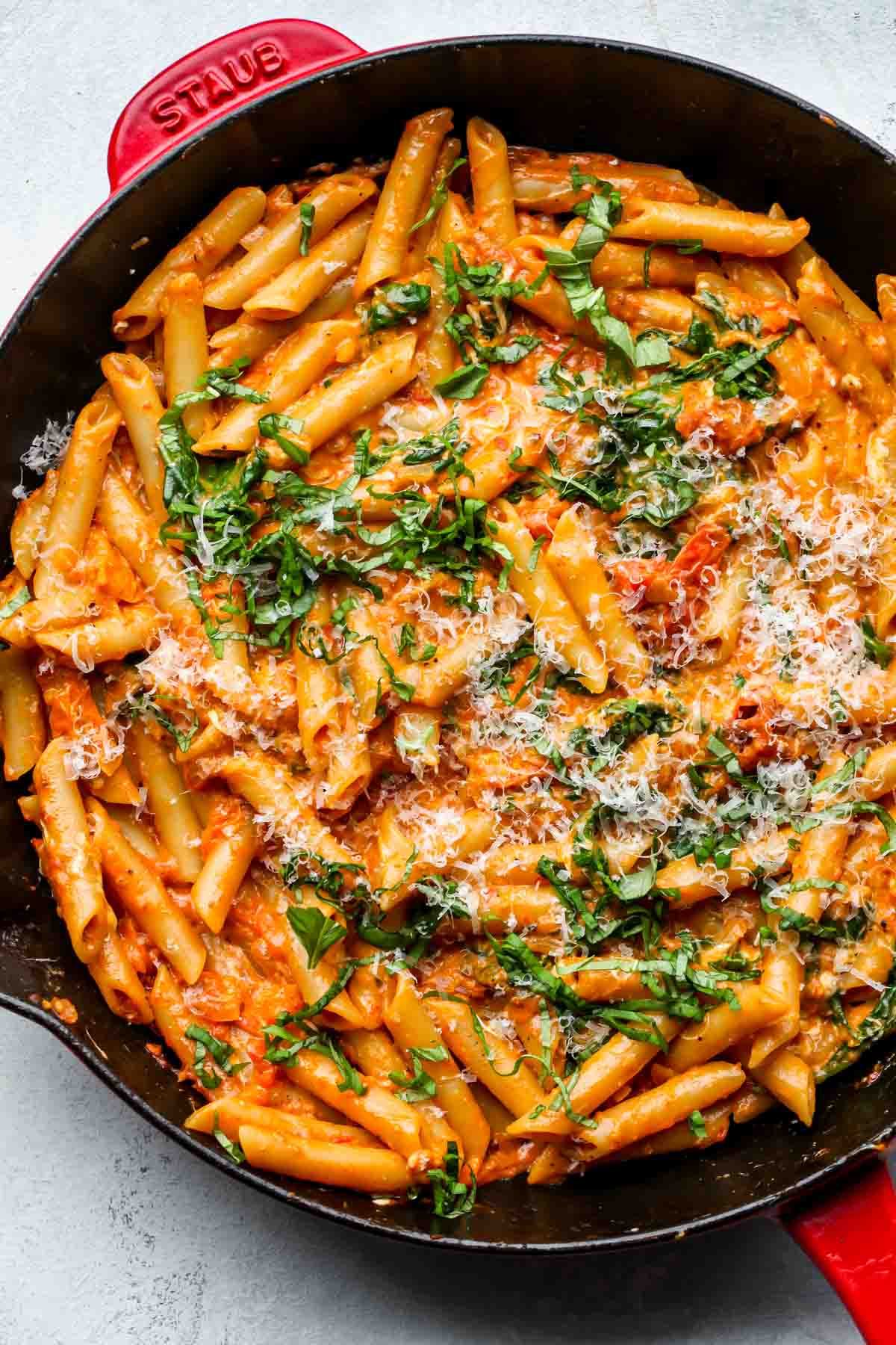 One pan creamy tomato pasta in a cast iron skillet topped with basil and parmesan.
