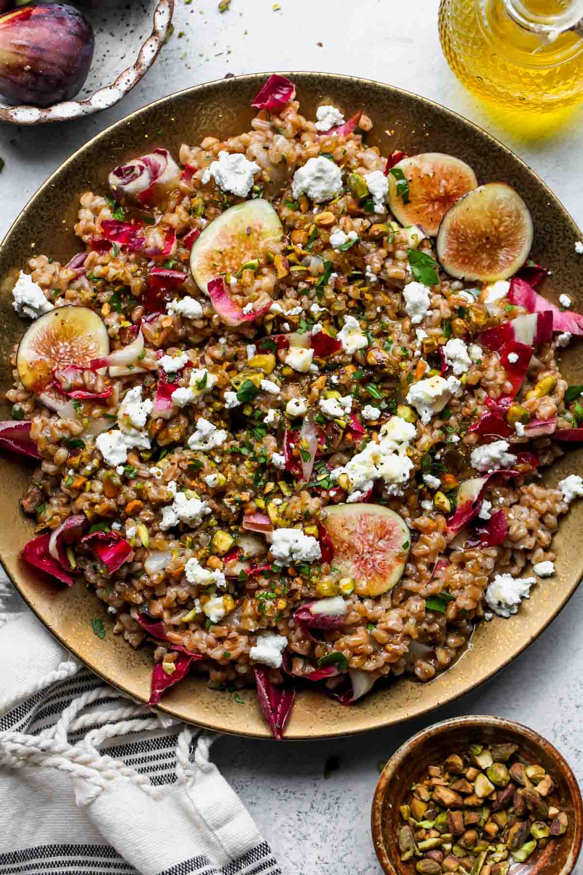 Warm farro salad with goat cheese, radicchio, and figs on a gold serving platter