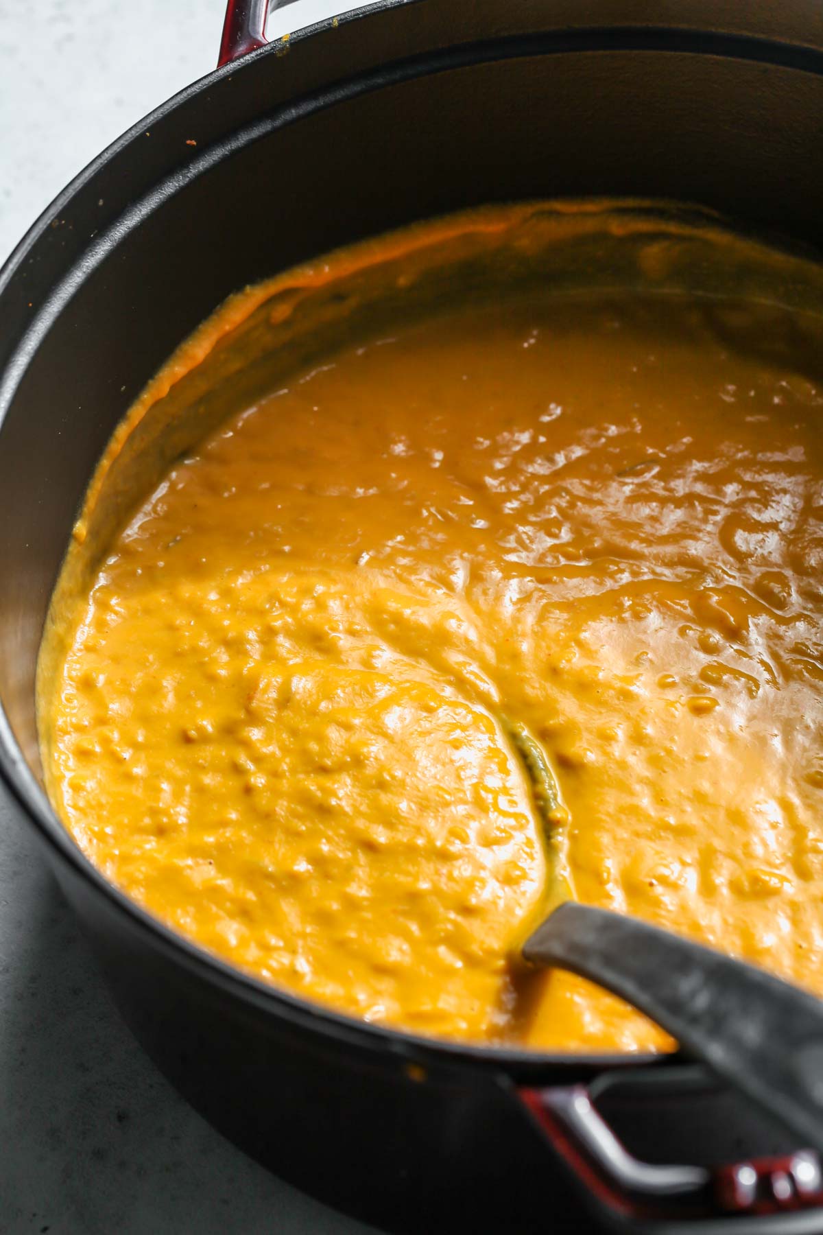 Dutch oven filled with soup with a ladle resting on the right side
