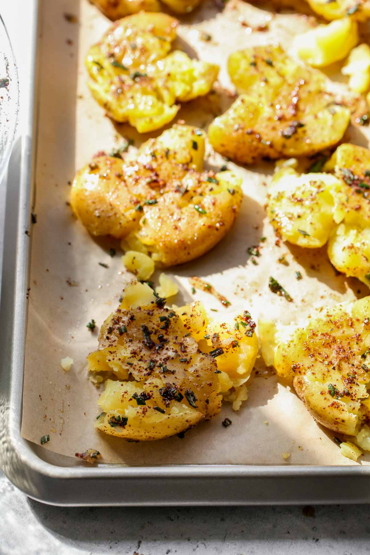Smashed potatoes being roasted on a rimmed baking sheet