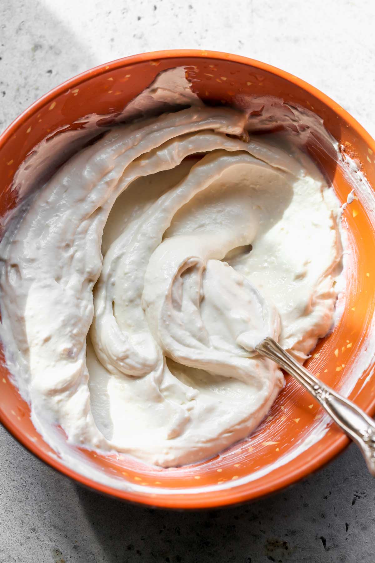 Roasted garlic dip being mixed in an orange bowl