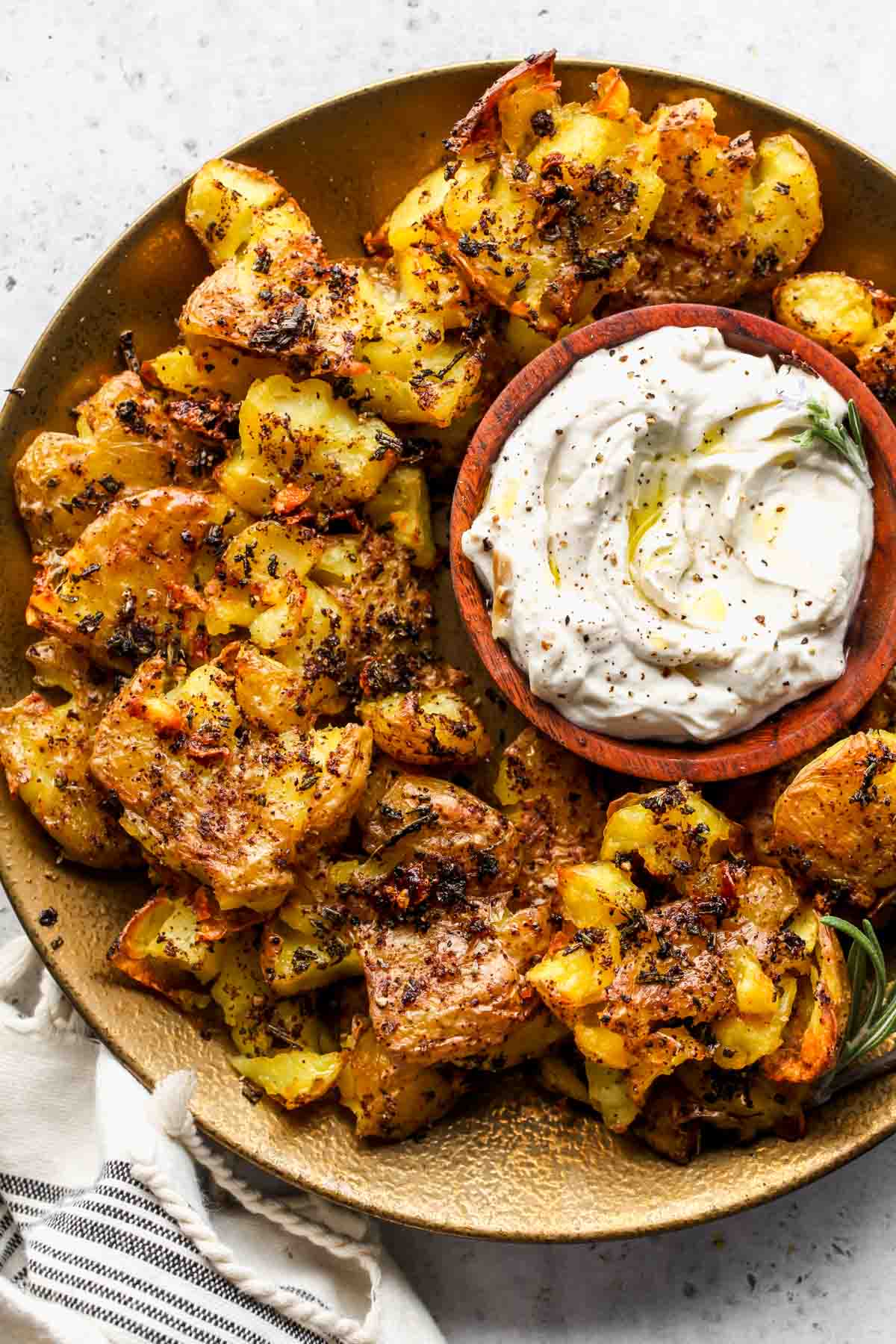 Rosemary smashed potatoes on a platter with roasted garlic dip