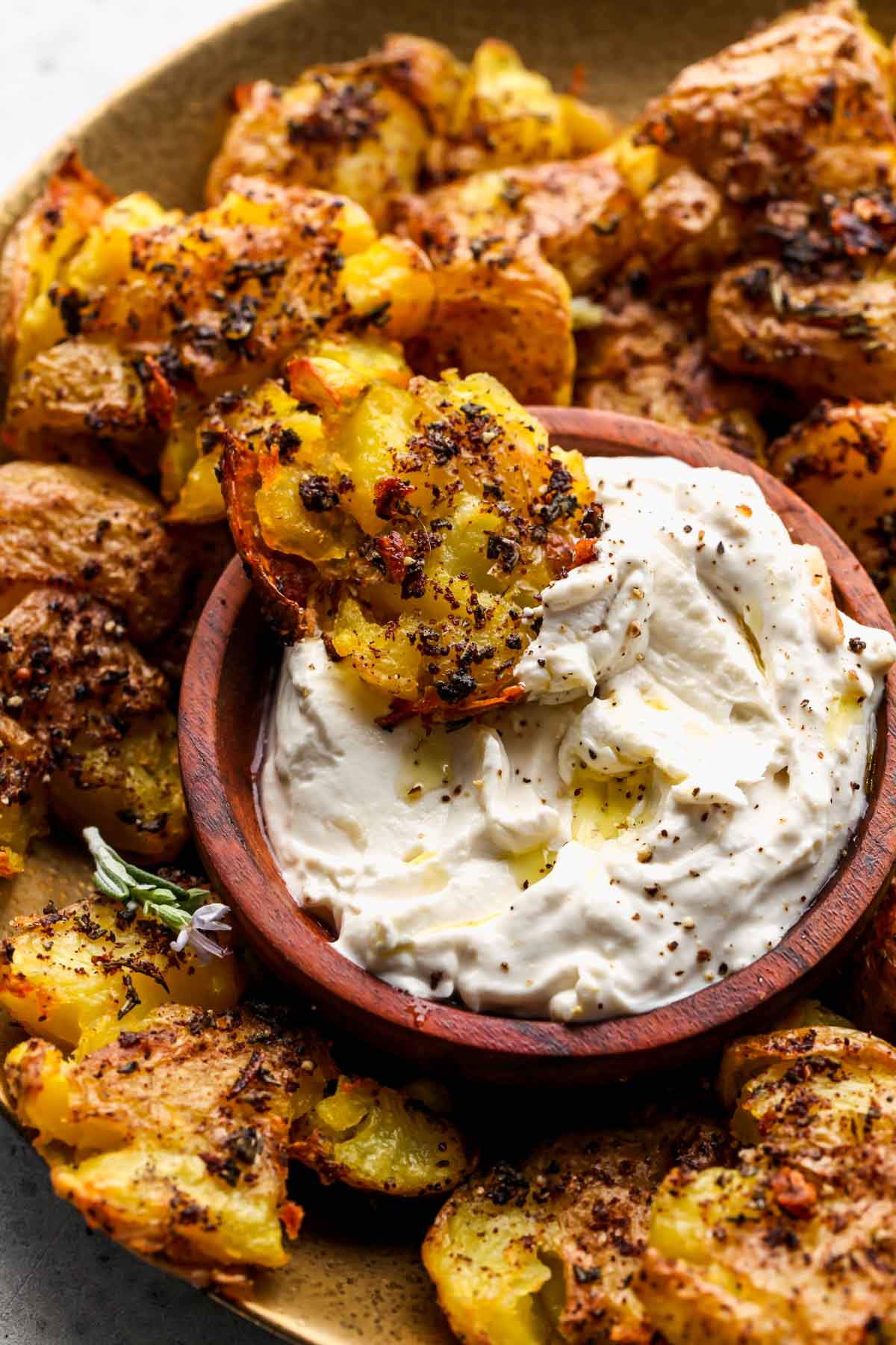 Rosemary smashed potato being dipped in a bowl of roasted garlic dip