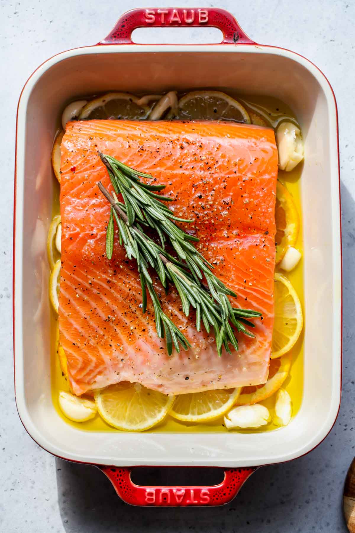 Piece of raw salmon in a red shallow pan getting ready to roast