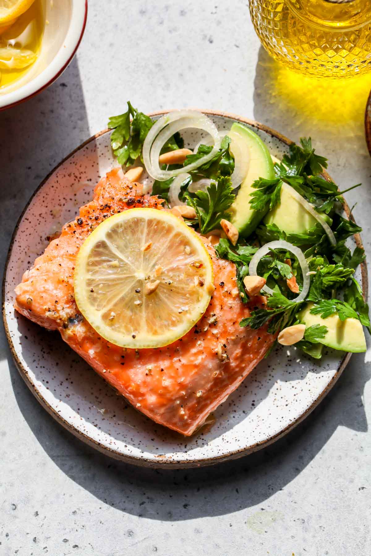 Single serving of salmon on a plate garnished with herb salad and sliced lemon