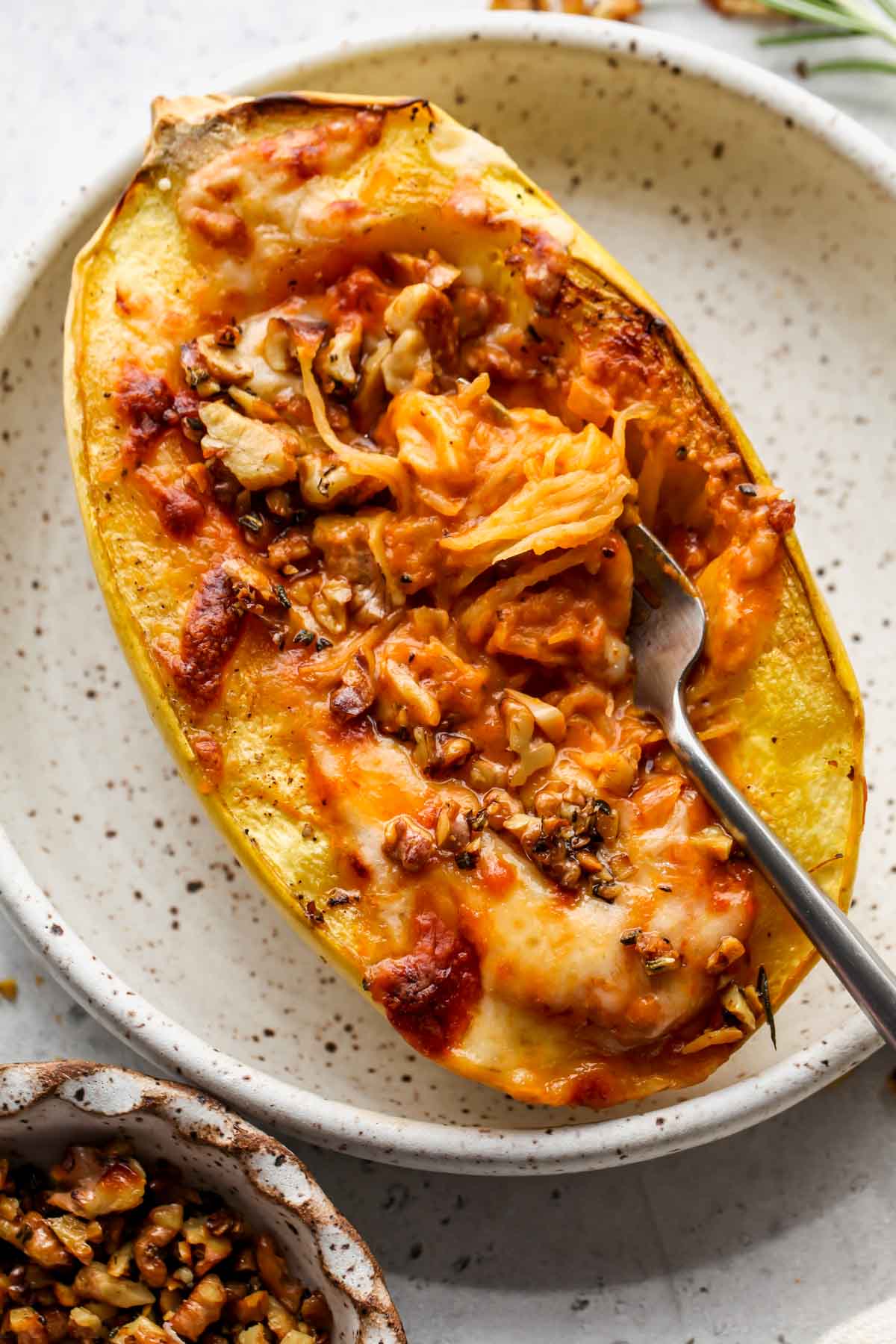 A fork twirling a serving of saucy spaghetti squash on a plate