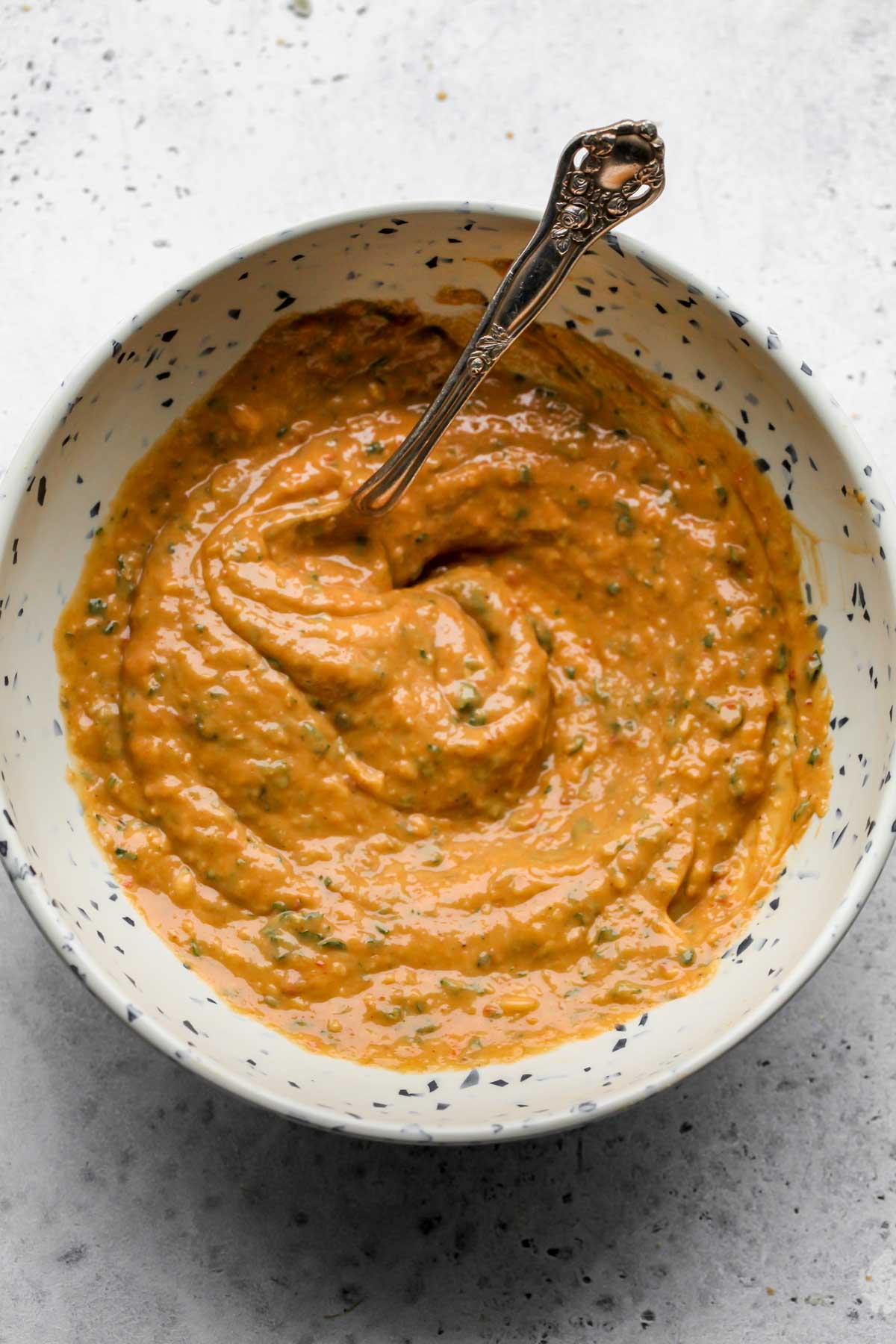 Dressing being stirred with a spoon in a white bowl