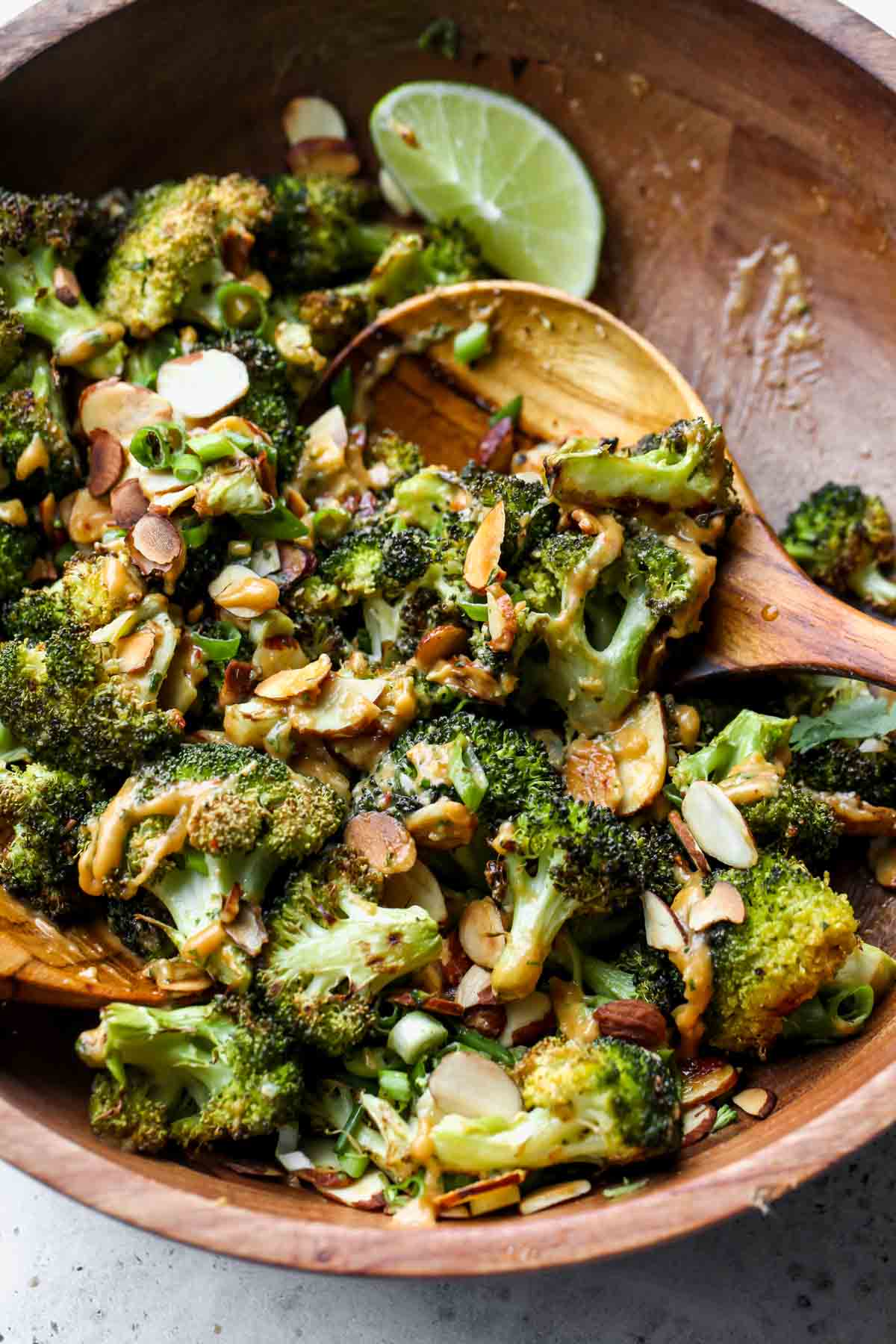 Broccoli salad being tossed in sweetgreen spicy cashew dressing
