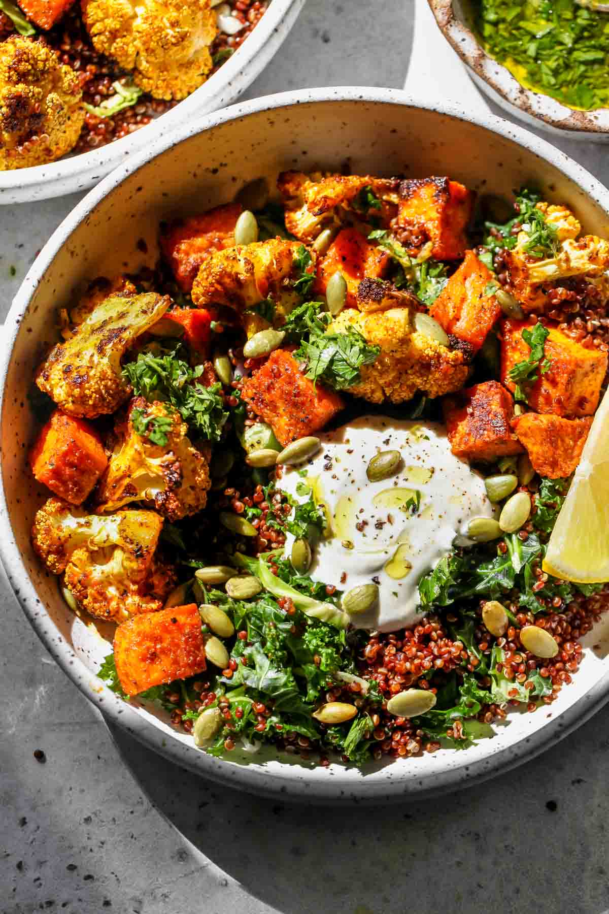 Sweet Potato Bowls with roasted cauliflower, quinoa, and yogurt sauce in a white bowl
